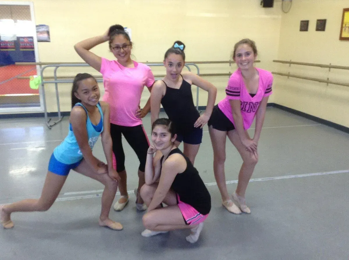 Five young people in a dance studio posing; wearing dance attire.