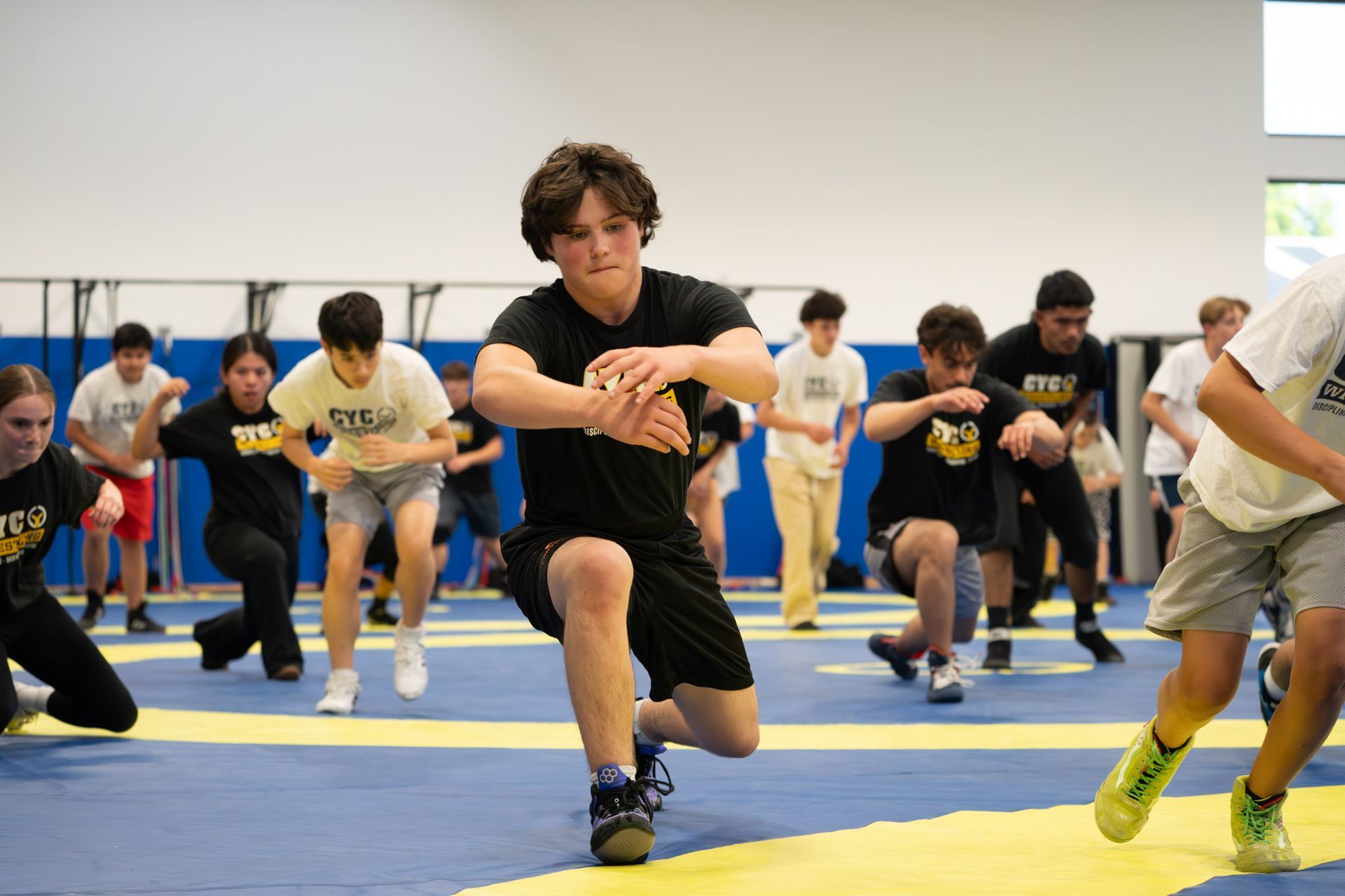 Martial arts instructor in a white uniform demonstrating a technique to two children in yellow belts.