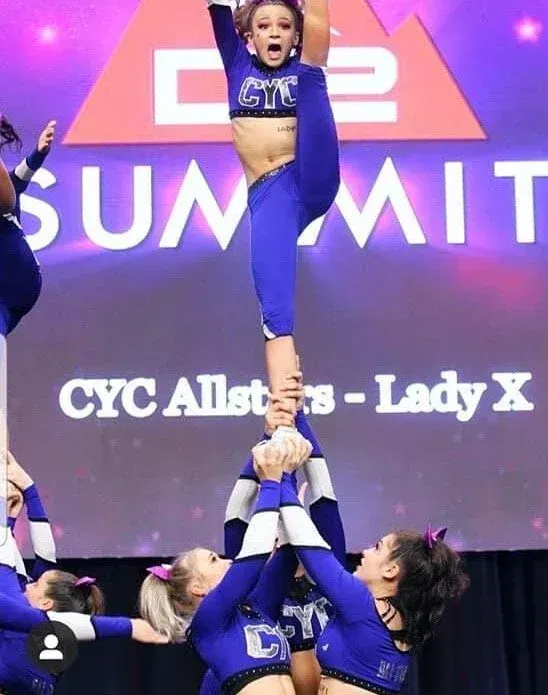 Cheerleaders in blue perform a split in a pyramid at the CYC Summit event.