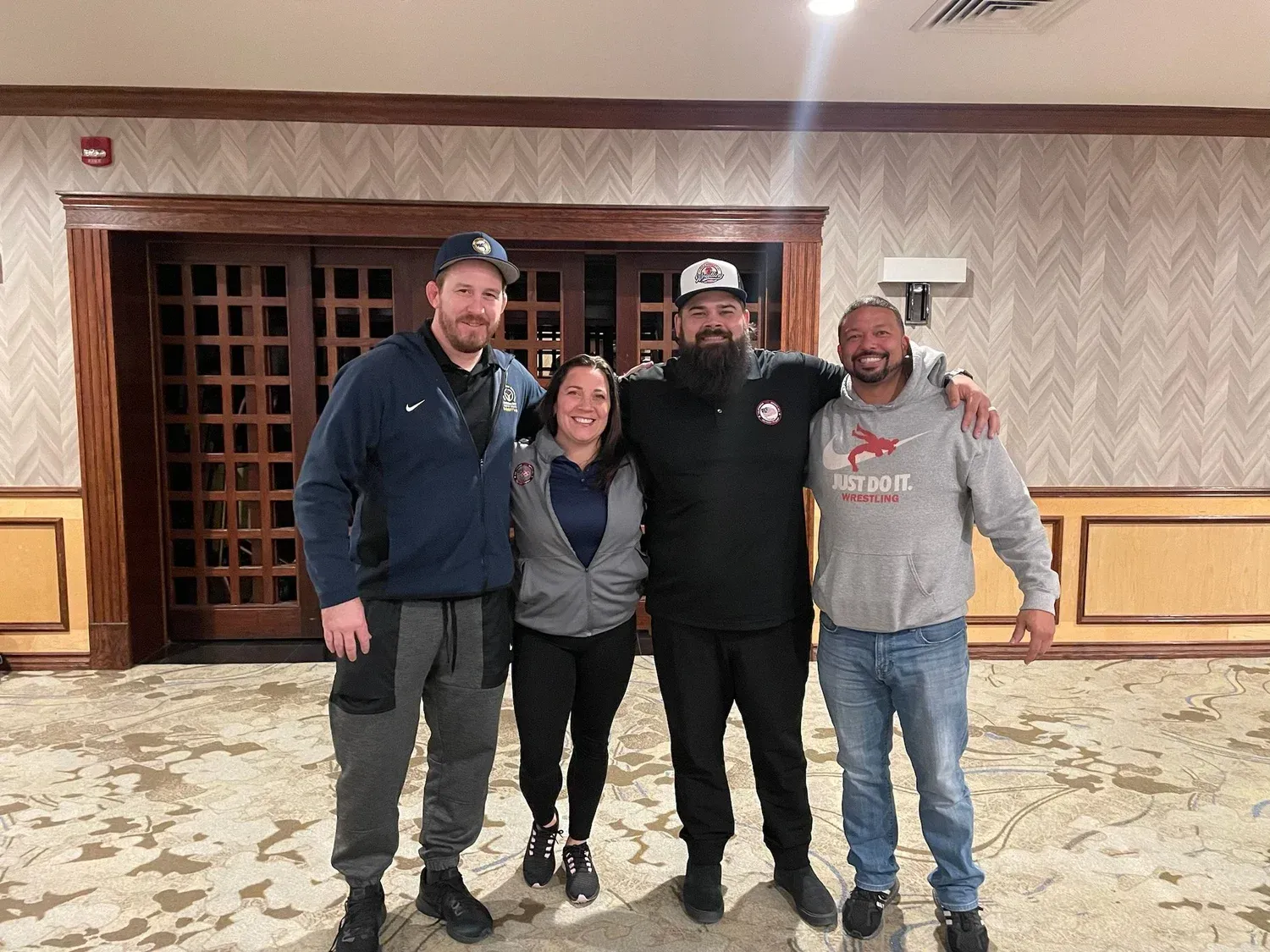 Four people standing closely, arms around each other.