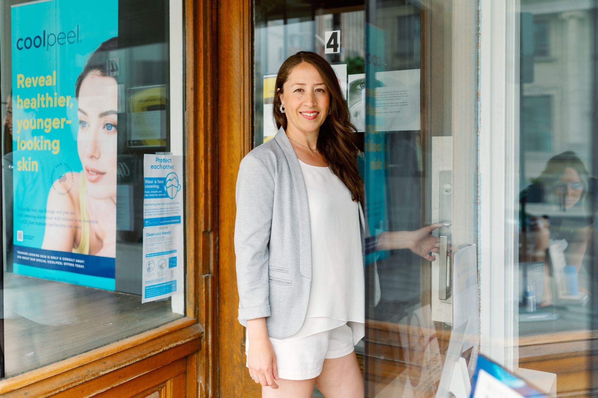 A woman is standing in front of a beauty clinic door.