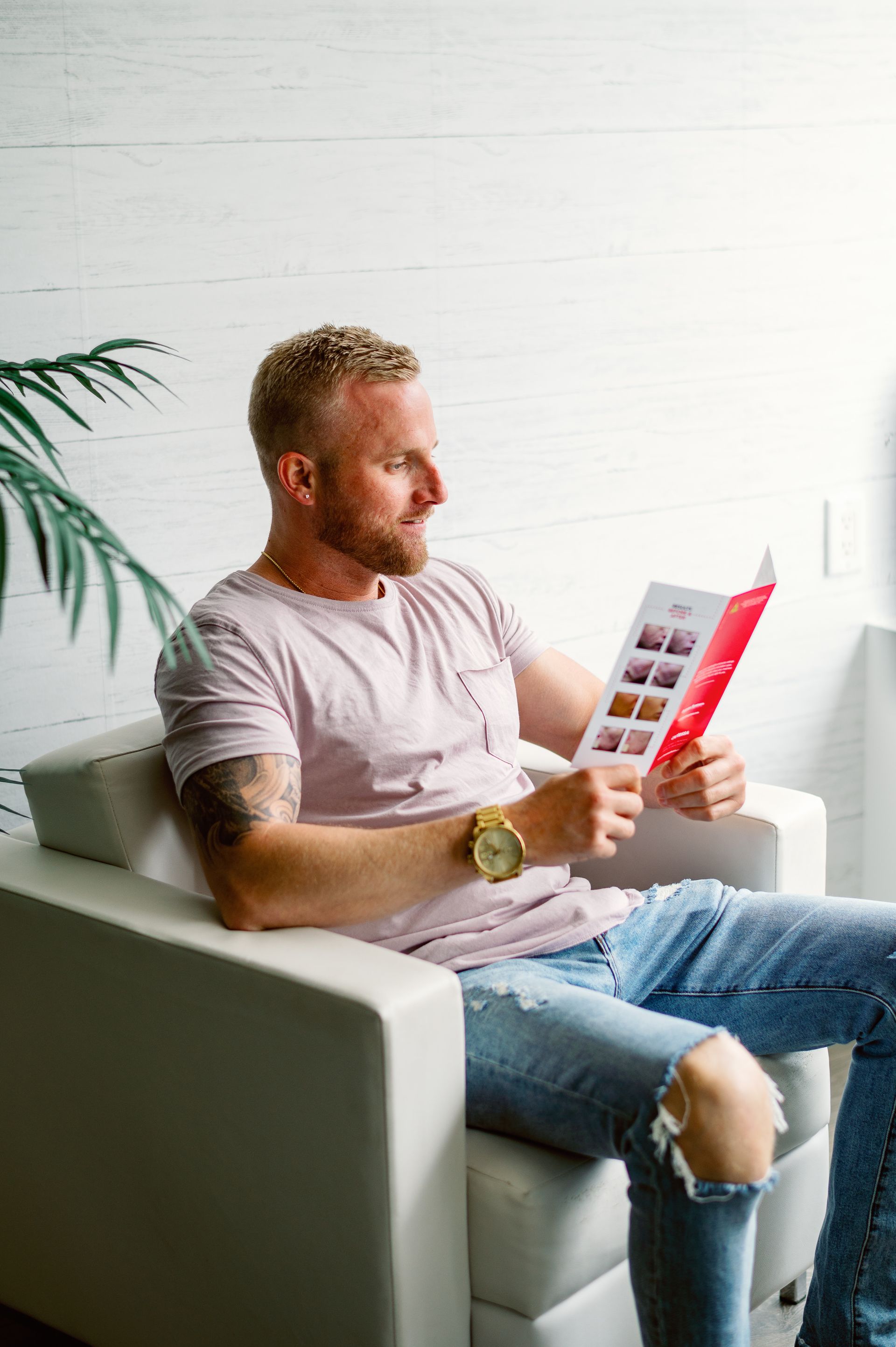 A man is sitting in a chair reading a book.