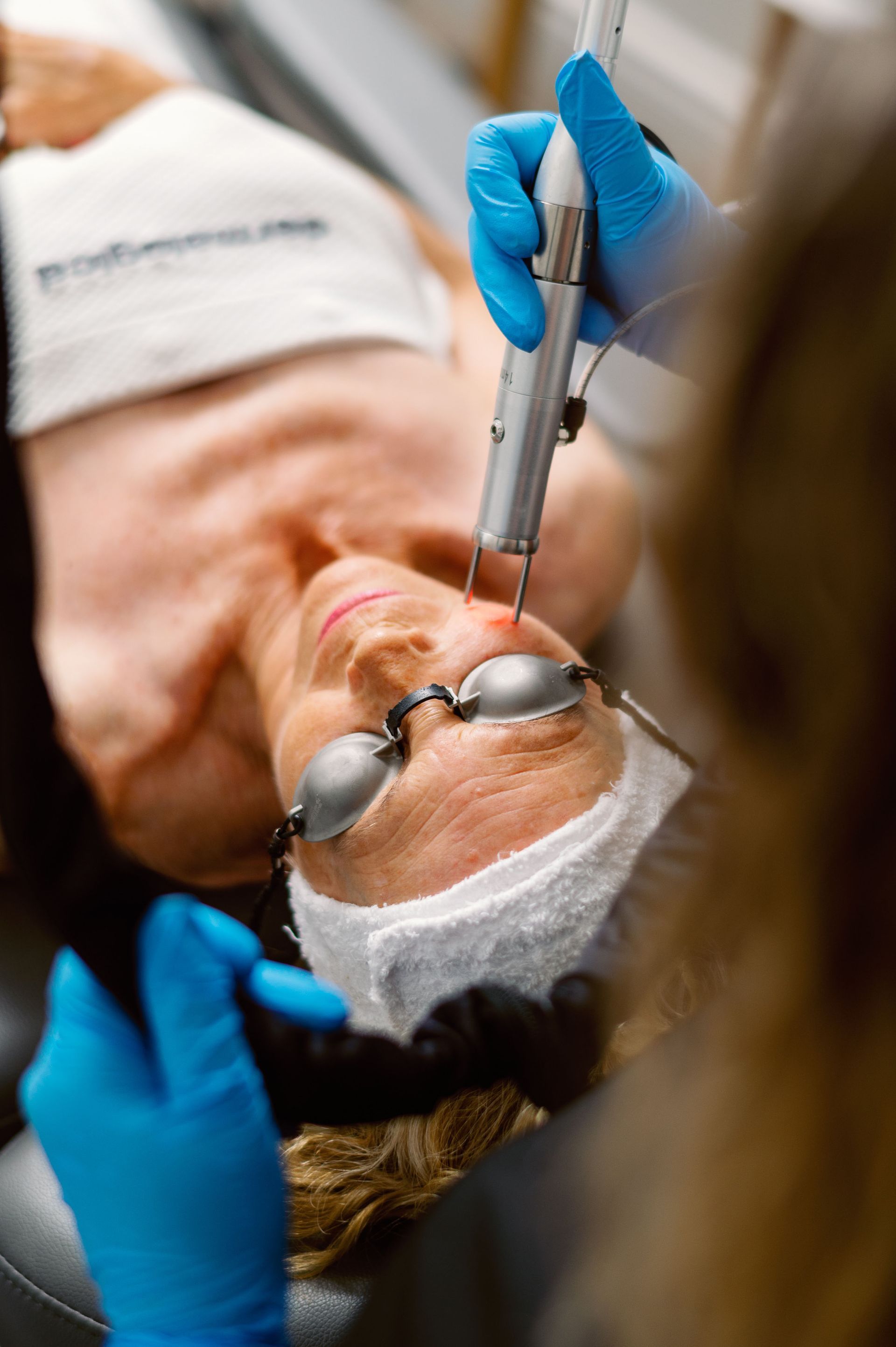 A woman is getting a laser treatment on her face.