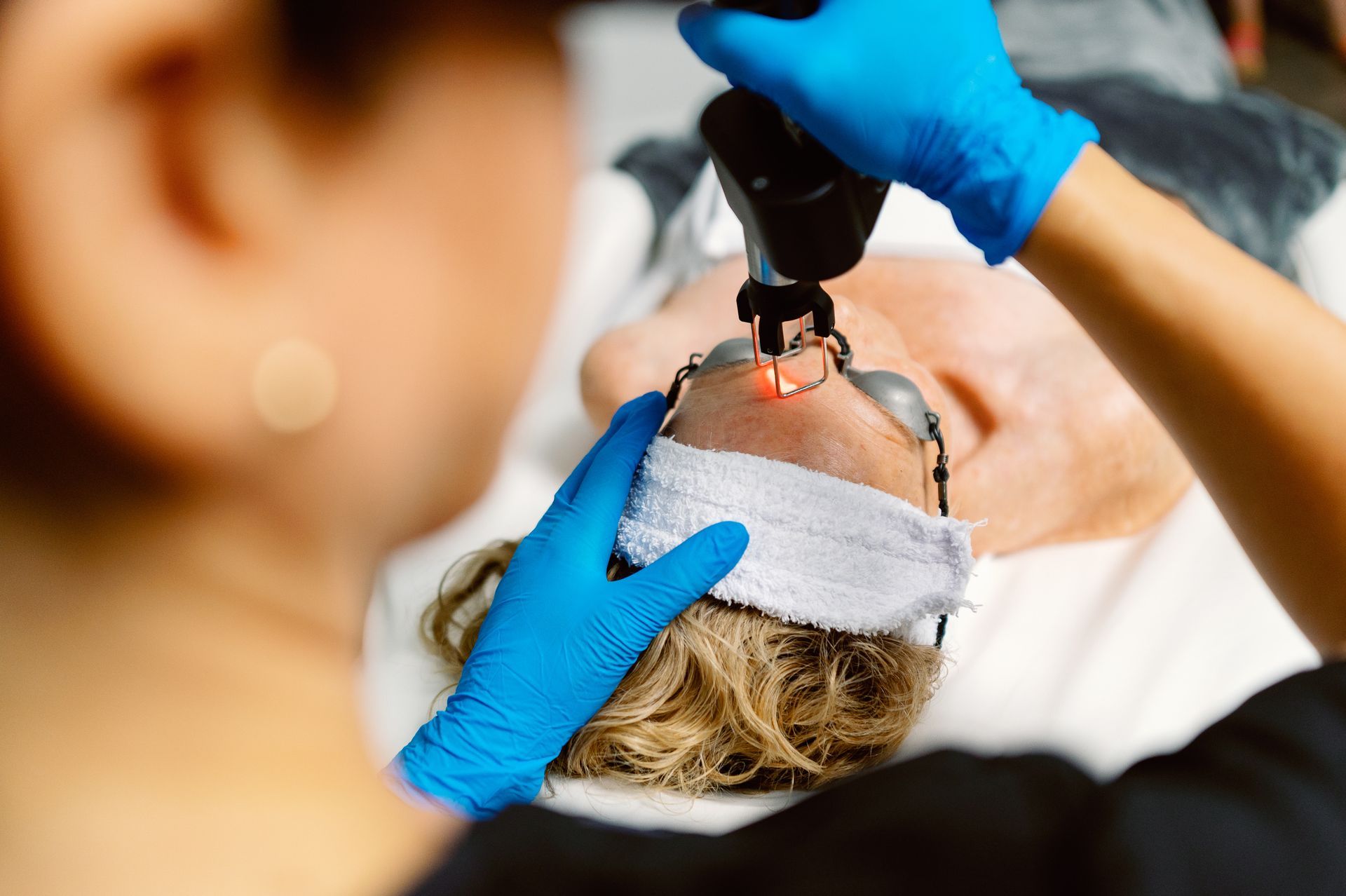 A woman is getting a laser treatment on her face.