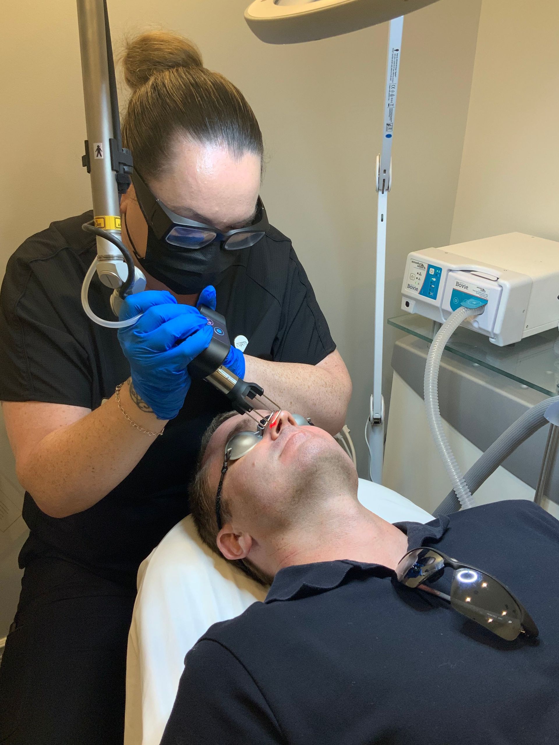 A woman is using a laser on a man 's face