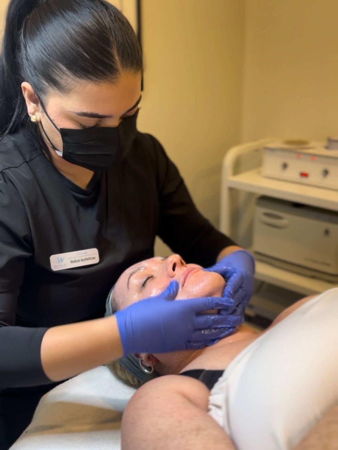 A woman wearing a mask and gloves is giving a man a facial treatment.