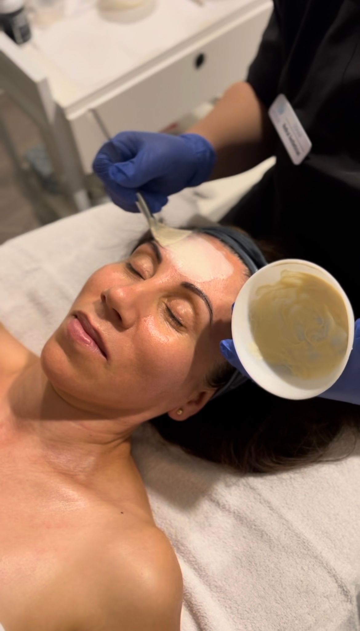A woman is laying on a bed getting a facial treatment.