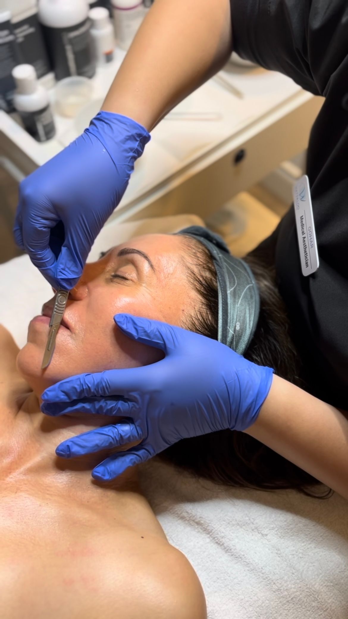 A woman is laying on a bed getting a facial treatment.