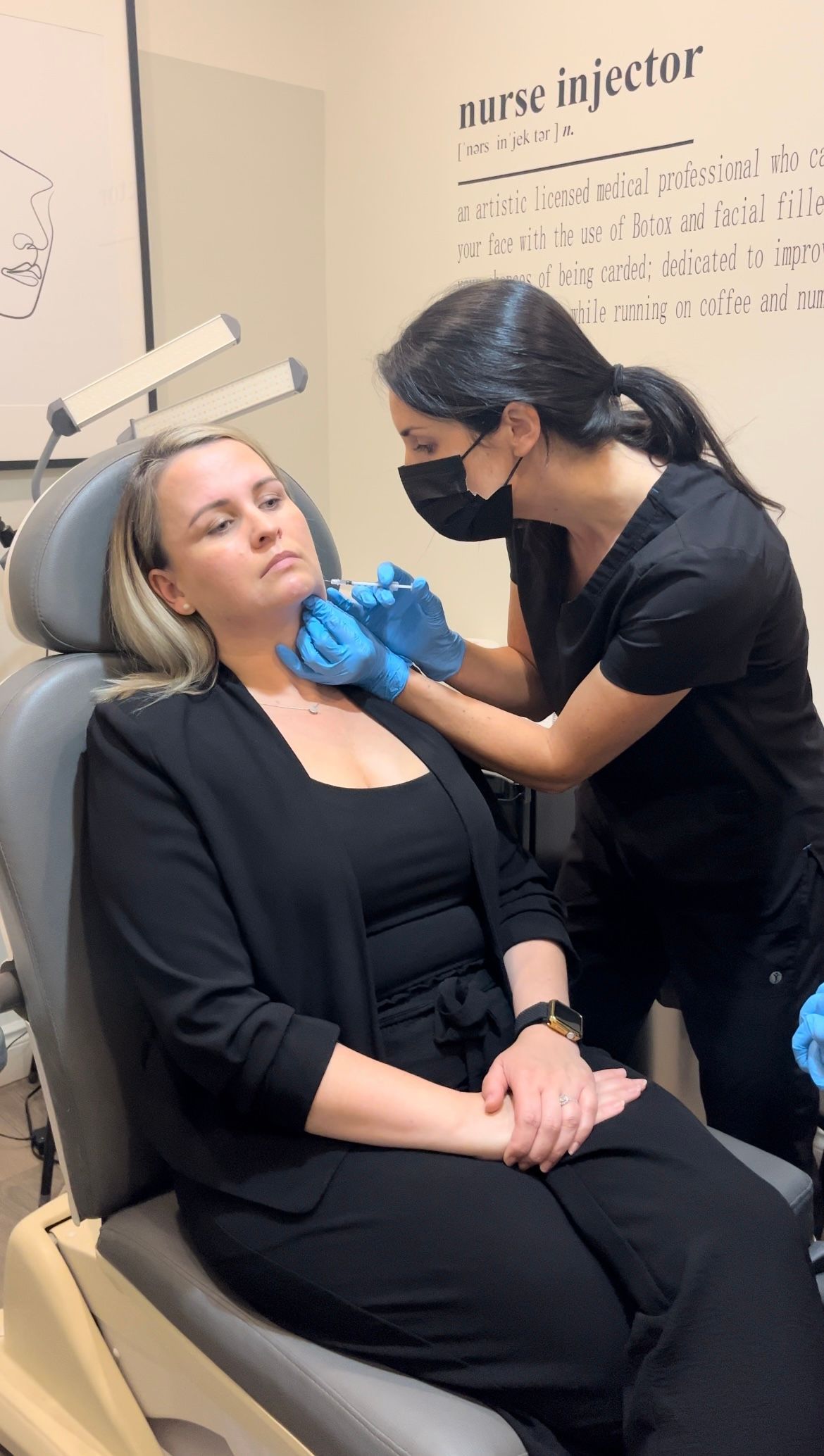 A woman is sitting in a chair getting an injection from a nurse.