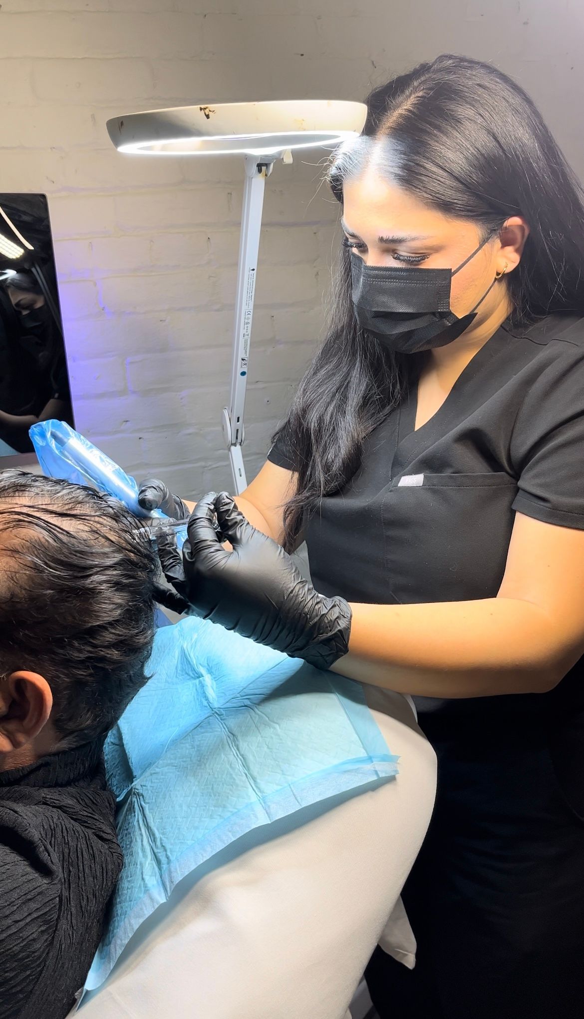 A woman is wearing a mask and gloves while working on a man 's hair.