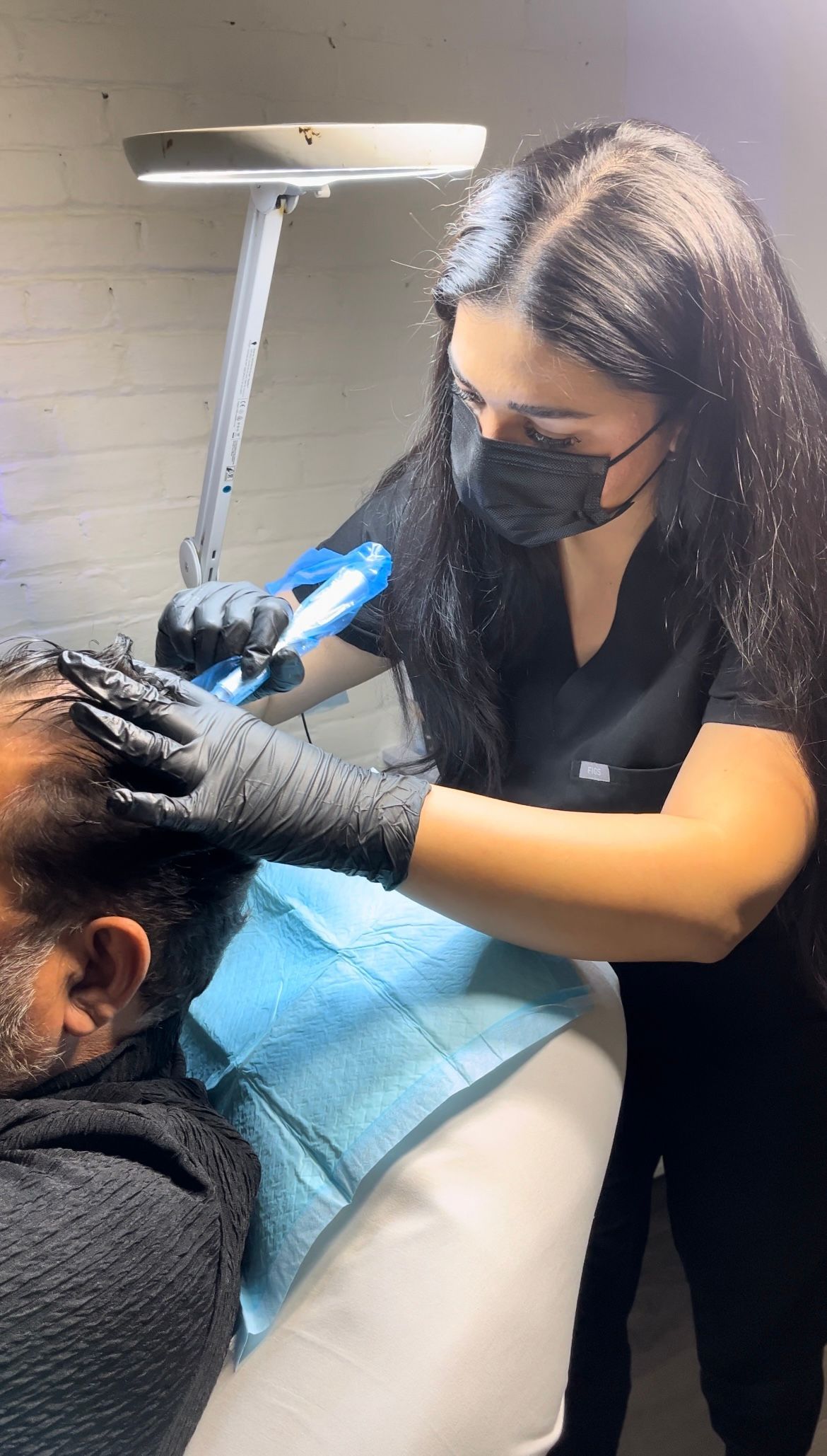 A woman is giving a man a hair treatment in a salon.