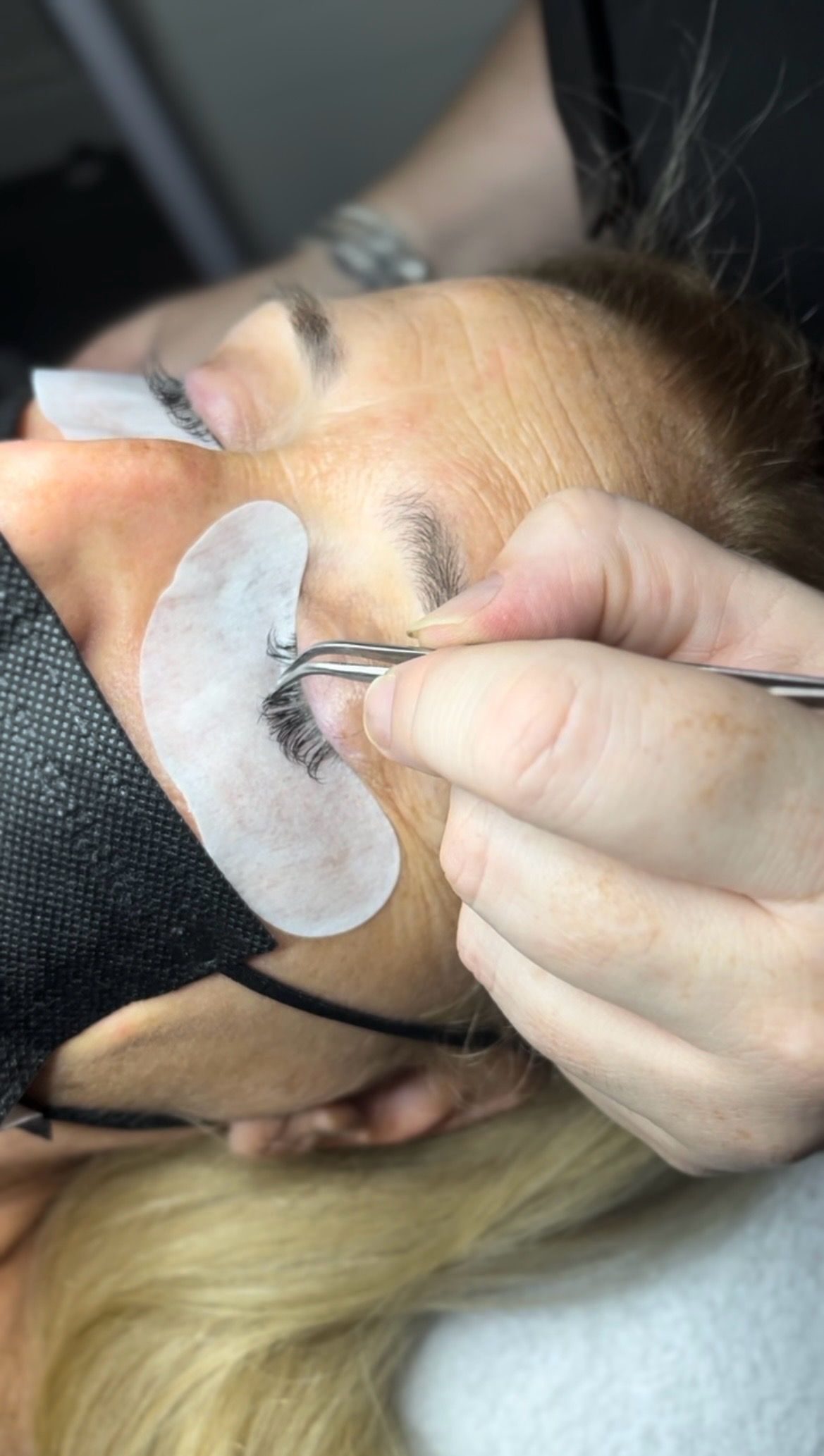 A woman is getting her eyelashes done at a salon.