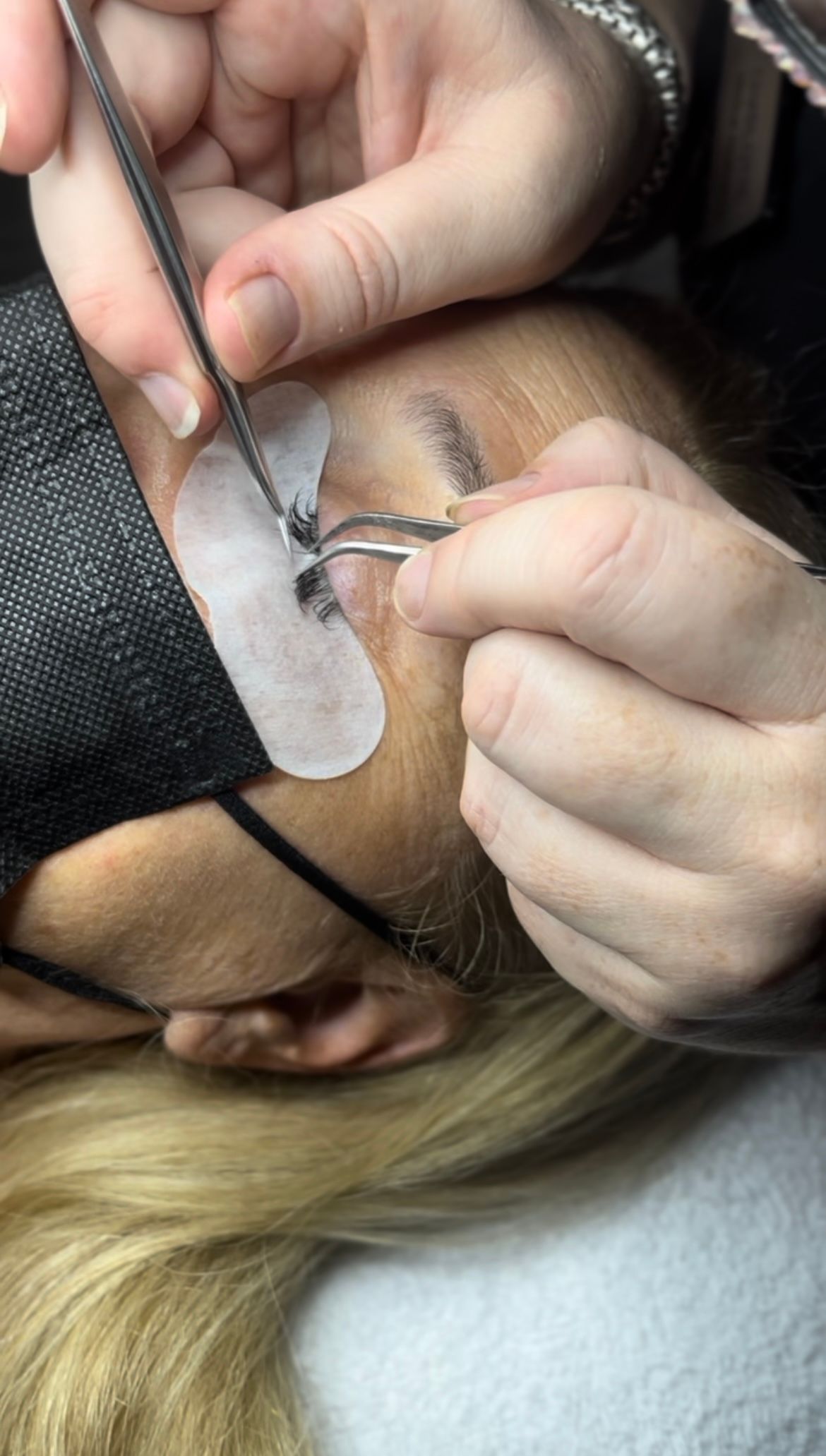 A person is applying eyelash extensions to a woman 's eye.
