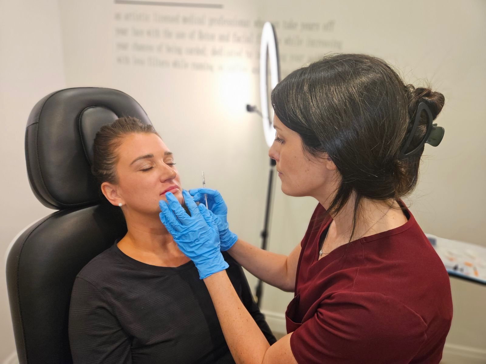 A woman is getting a botox injection in her lip while sitting in a chair.