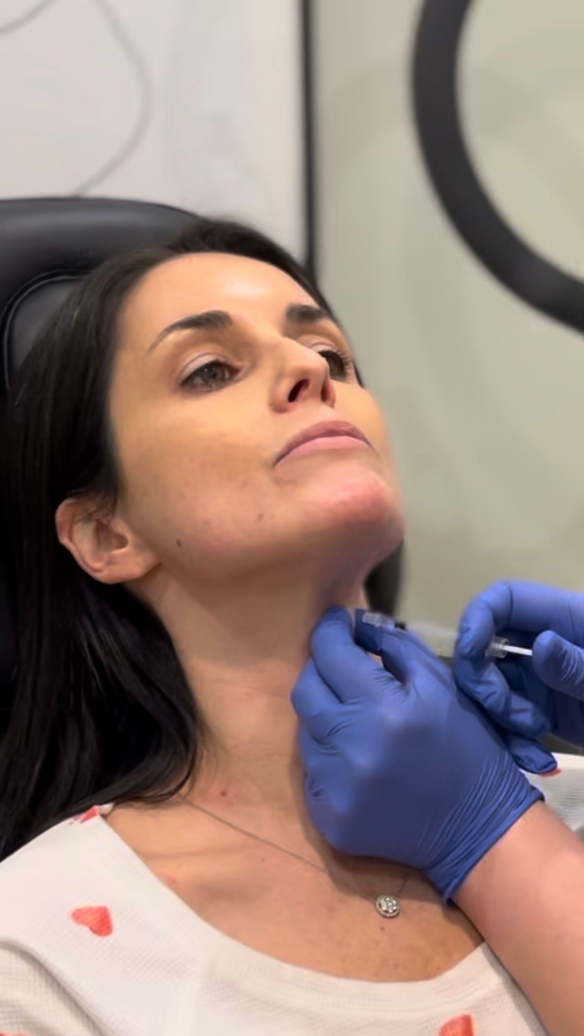 A woman is getting a botox injection in her neck.