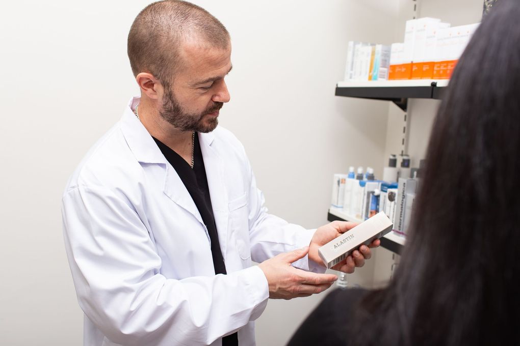 A man in a lab coat is holding a box in front of a woman.