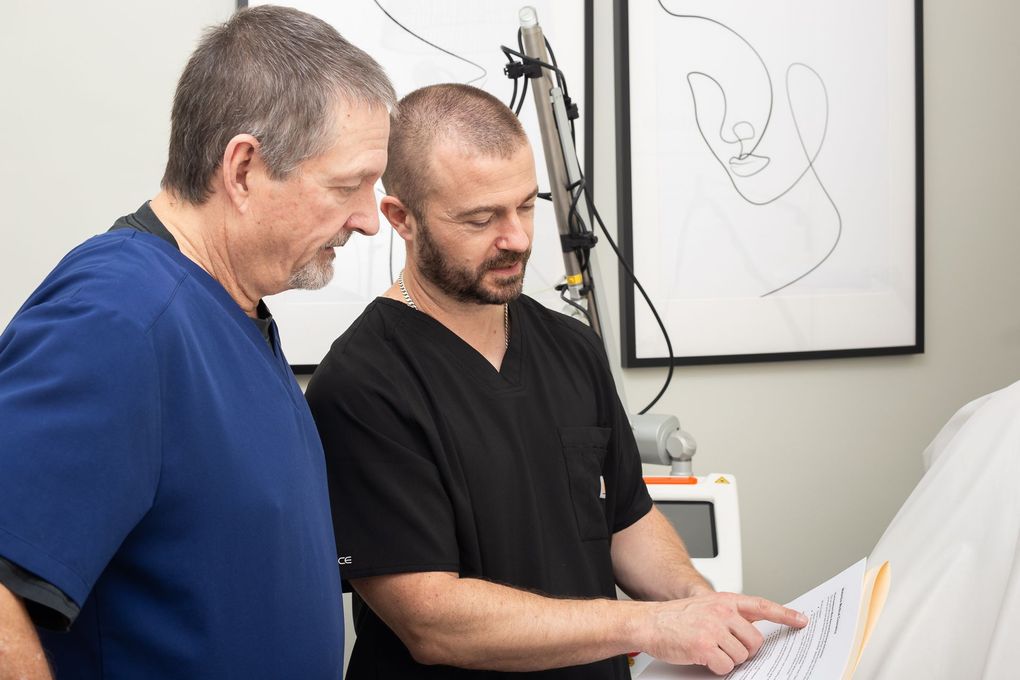 Two men in scrubs are looking at a piece of paper.