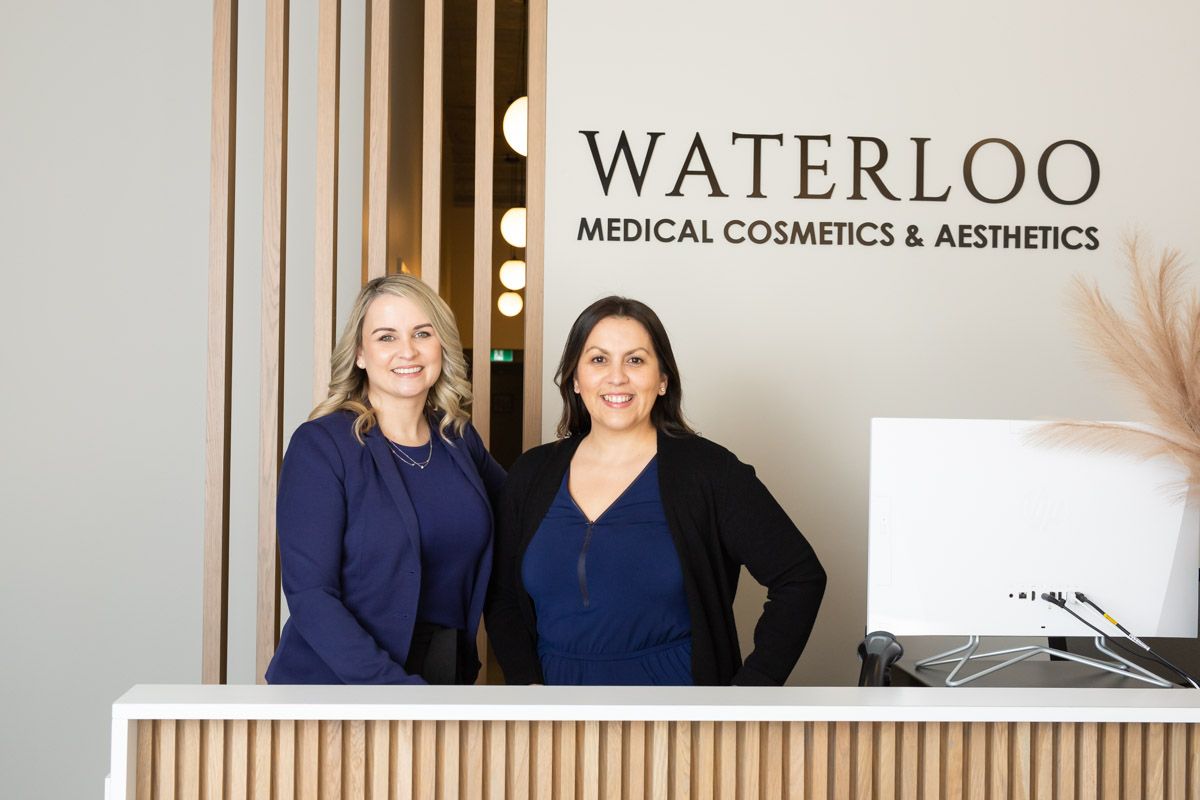 Two women are standing in front of a medical cosmetics and aesthetics counter.