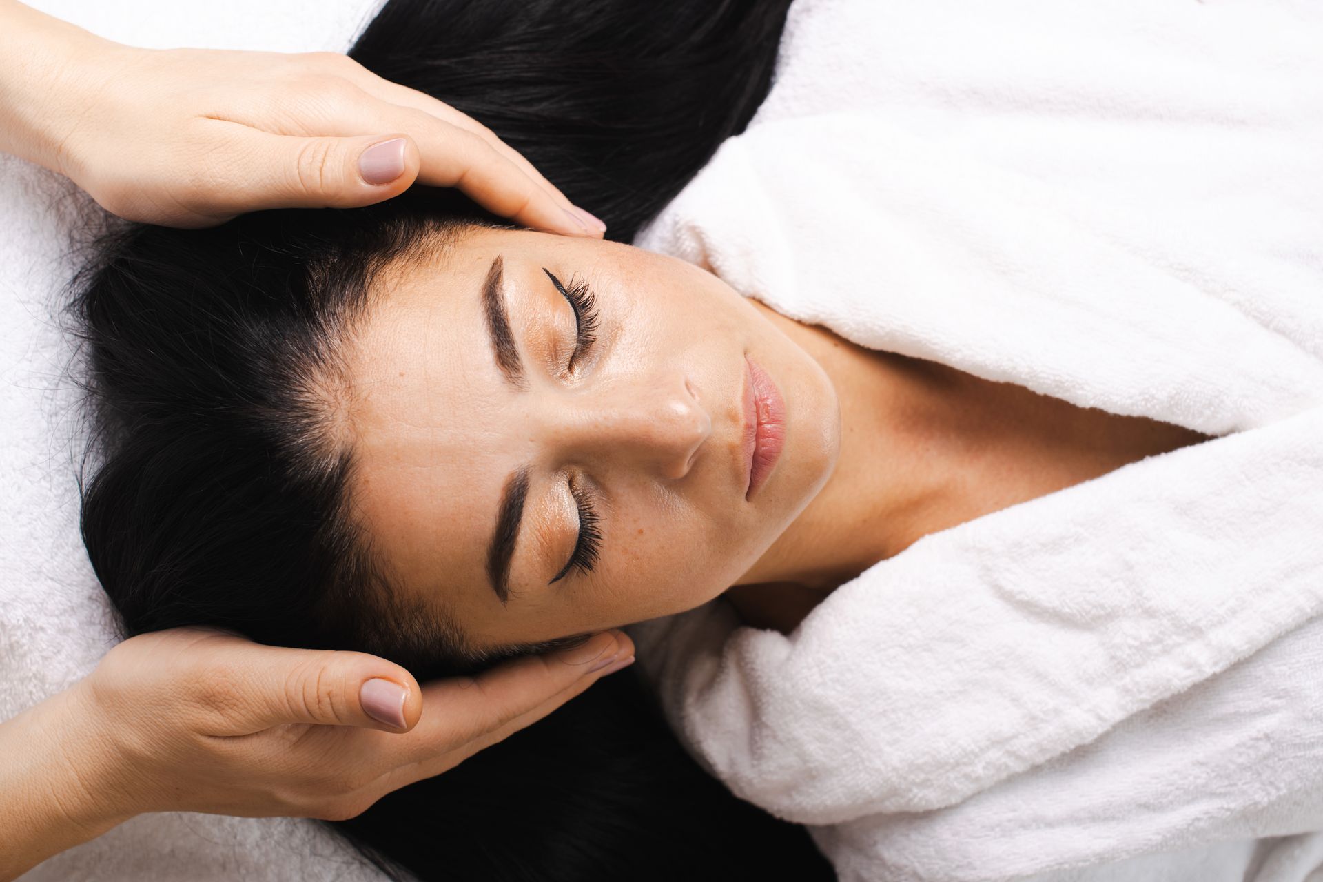 A woman is getting a face massage at a spa.