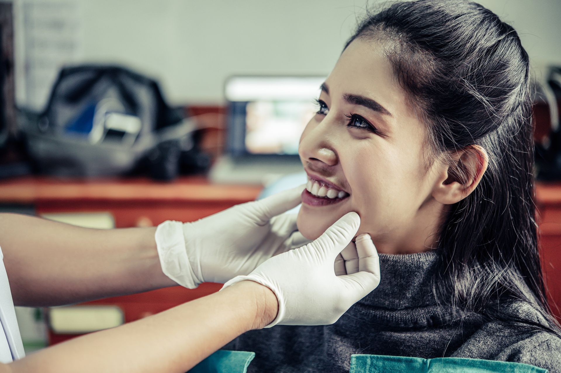 A woman is smiling while having her face examined.