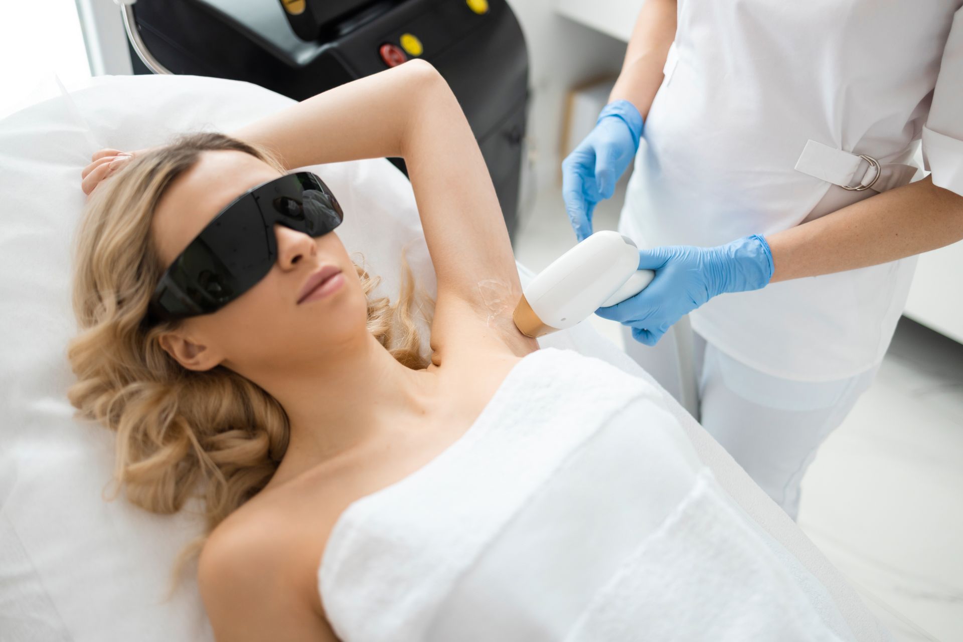 A woman is getting a laser hair removal treatment on her armpit.