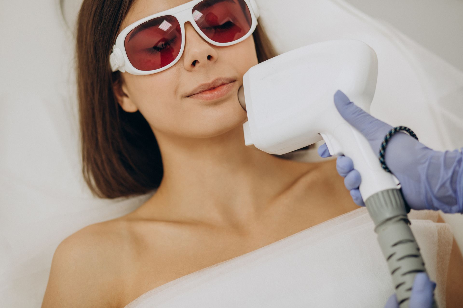 A woman is getting a laser hair removal treatment on her face.