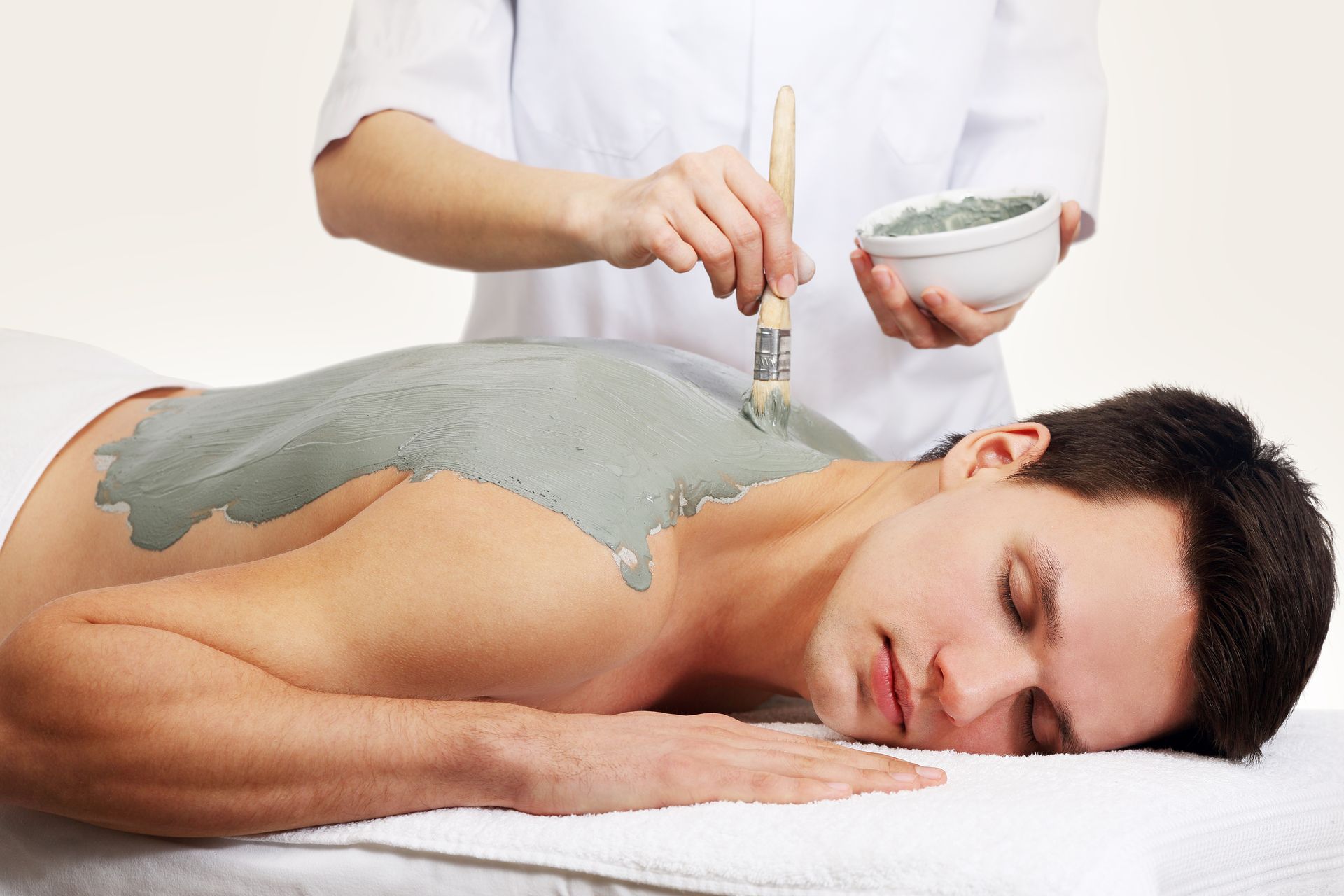 A man is getting a clay treatment on his back.