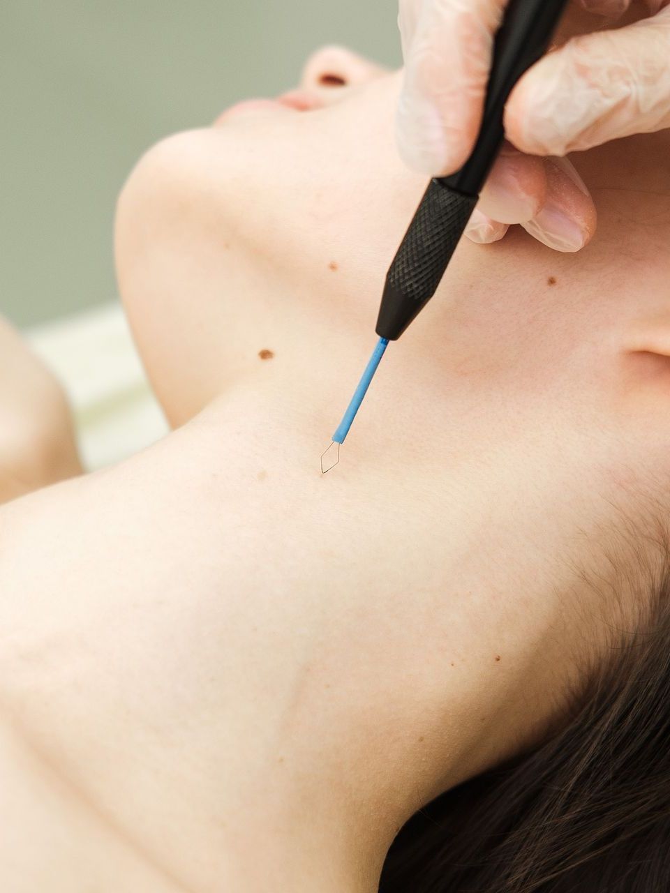 A woman is getting a laser treatment on her neck.