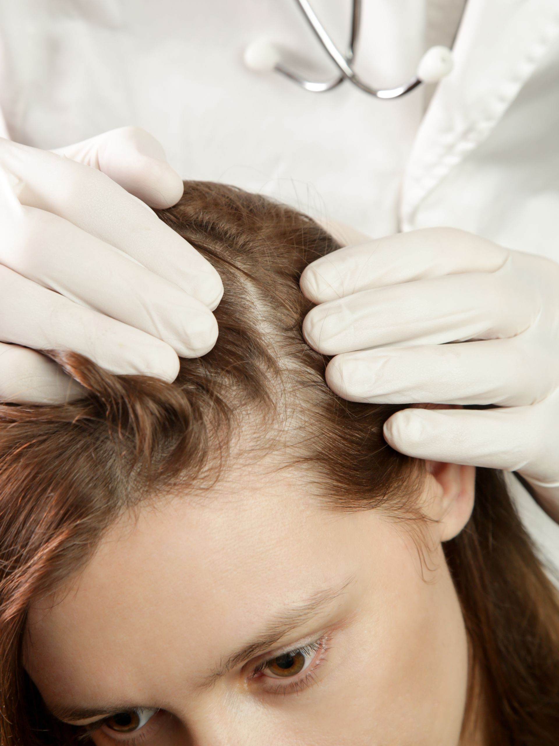 A doctor is examining a woman 's hair with a stethoscope.