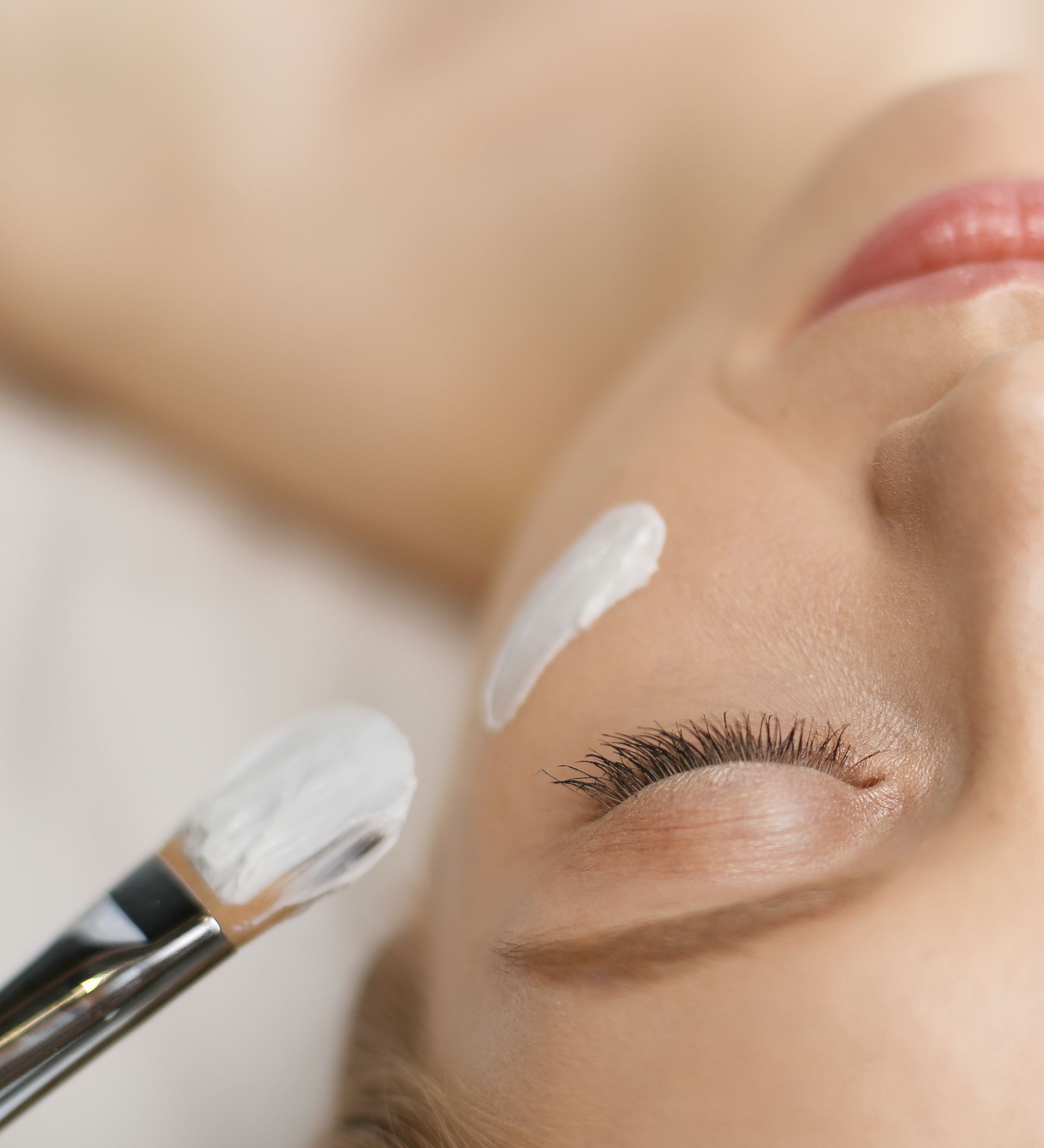 A woman is getting a facial treatment with a brush.