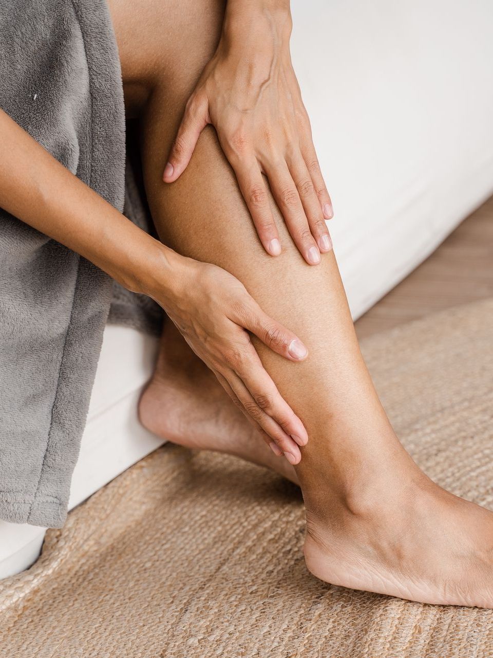 A woman is sitting on a couch and touching her leg.