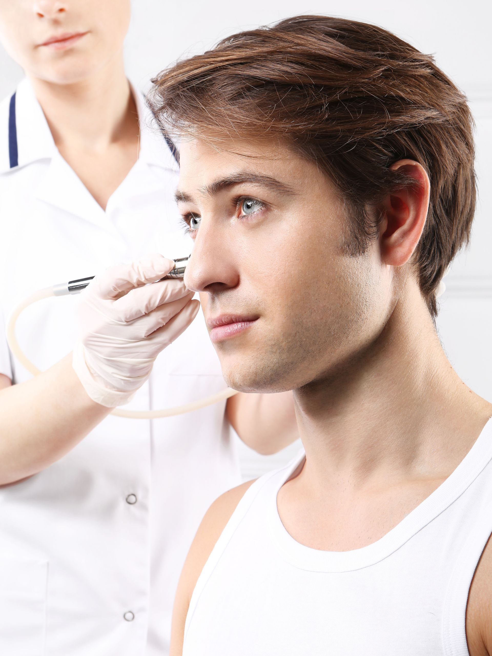 A man is getting an injection in his nose by a nurse.