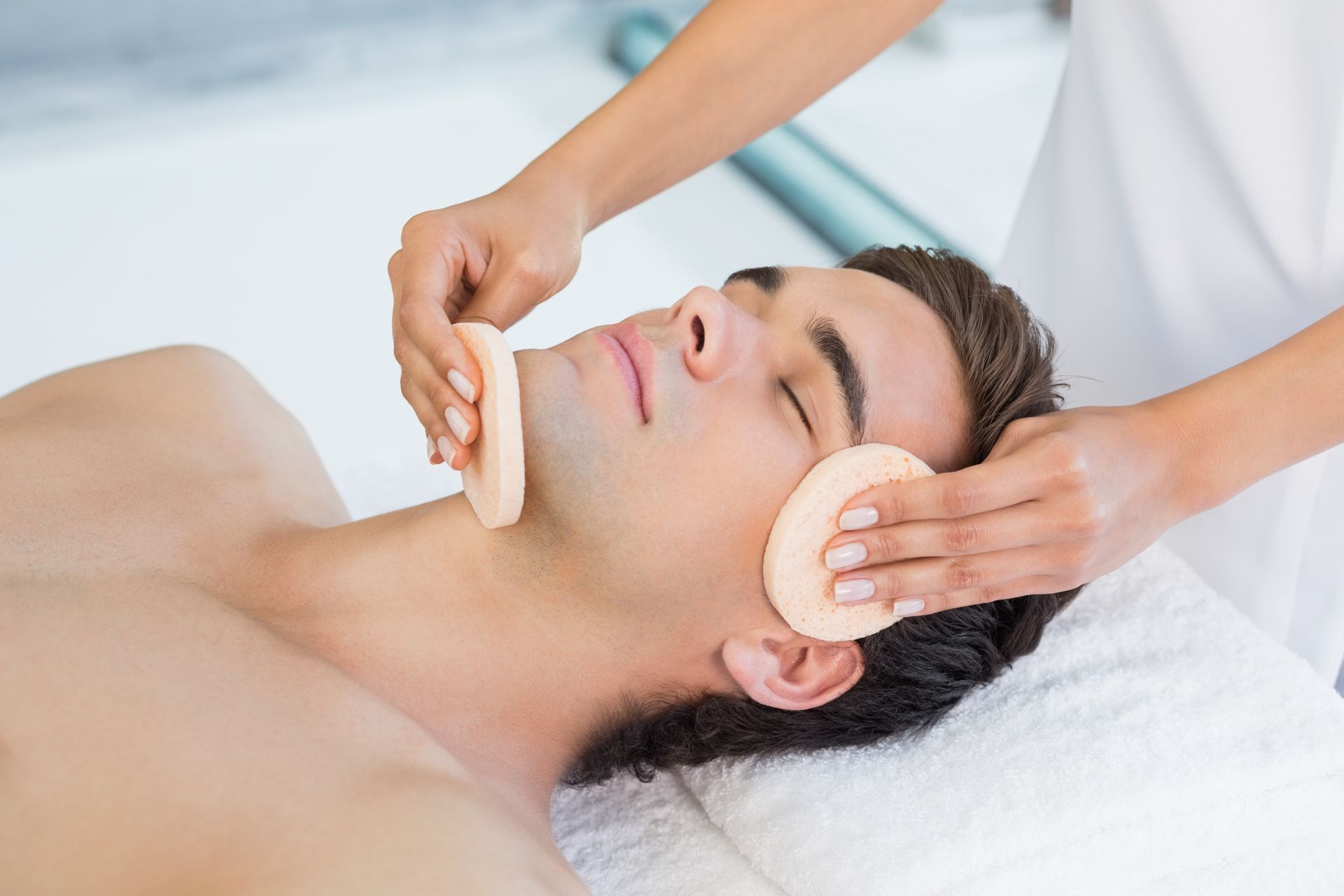 A man is getting a facial treatment at a spa.