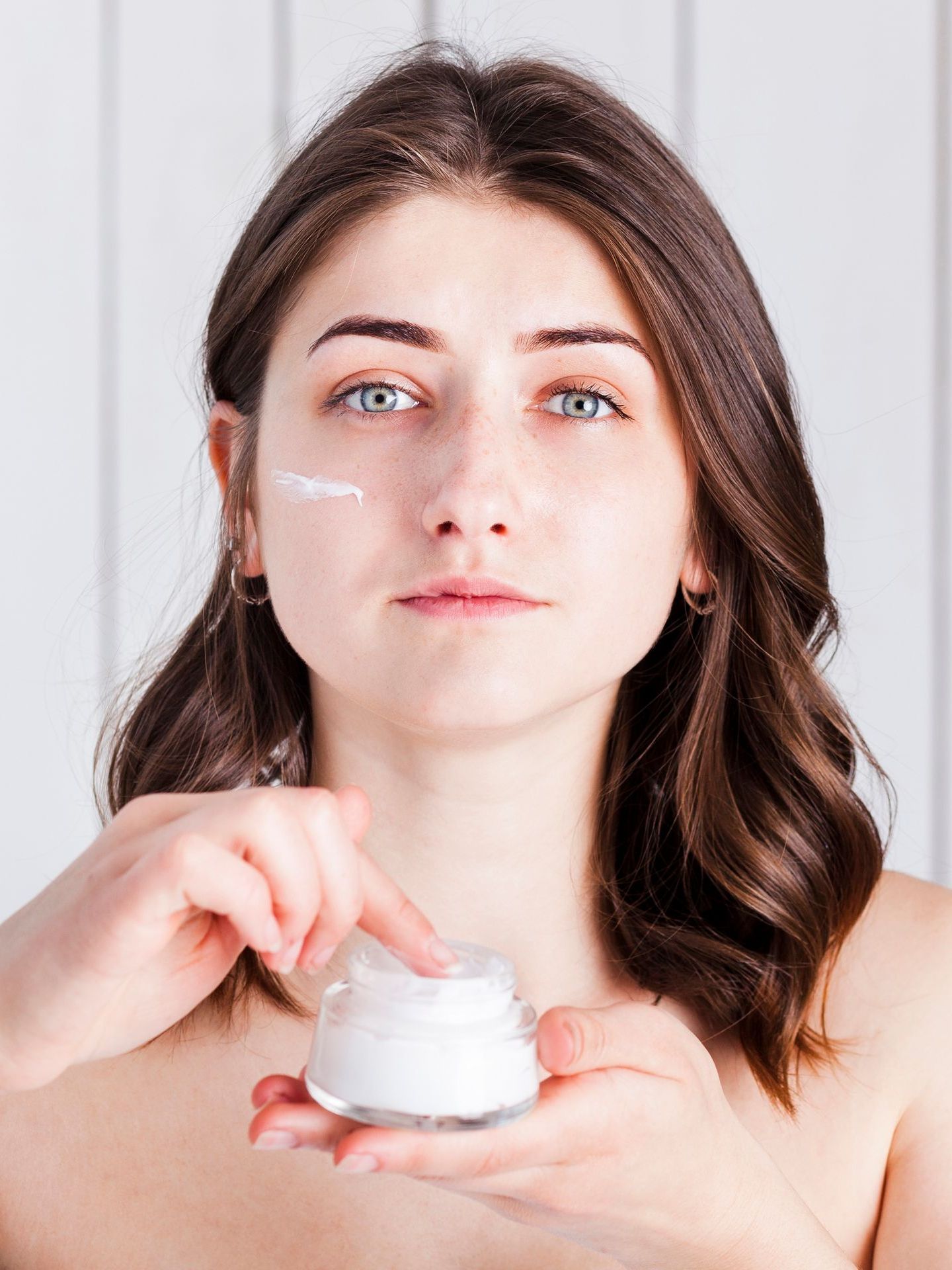 A woman is applying a cream to her face