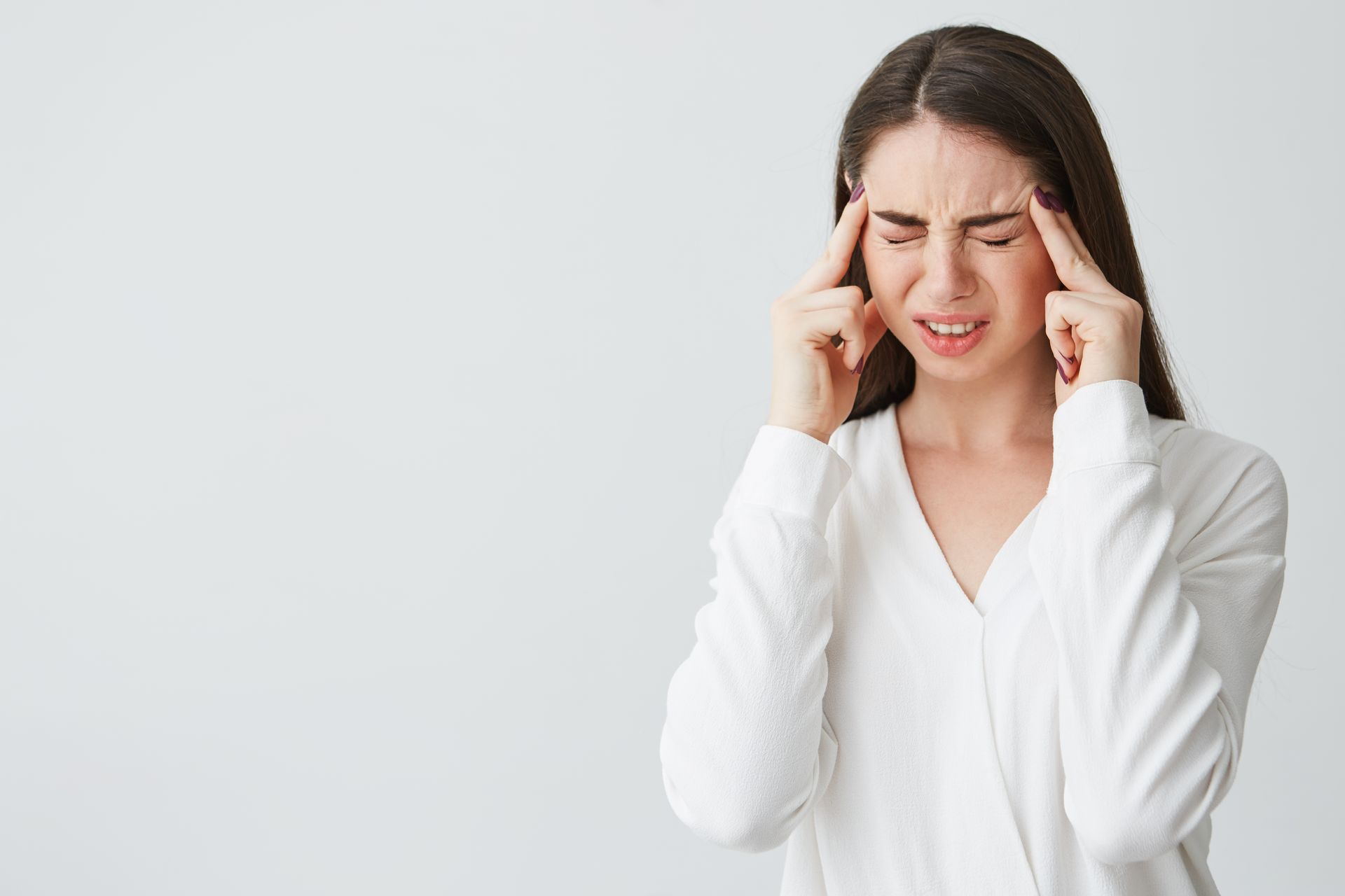 A woman is holding her head because she has a headache.