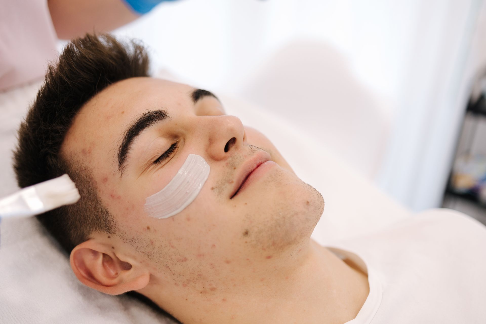 A young man is getting a facial treatment at a beauty salon.