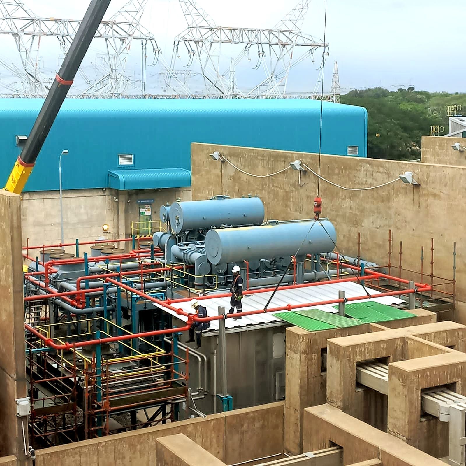 A crane is lifting a large blue tank on top of a building.