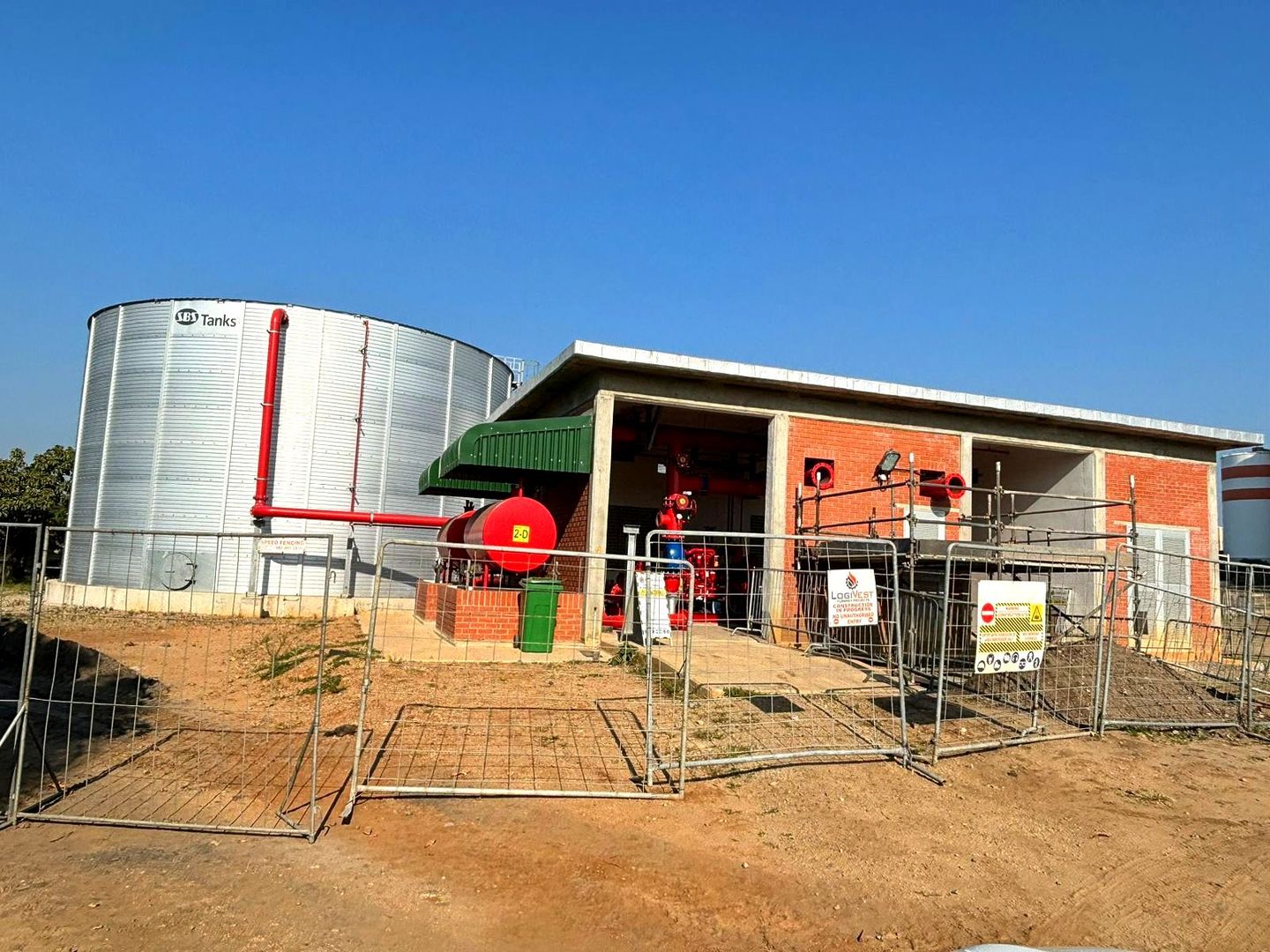 A building with a fence around it and a large tank in the background