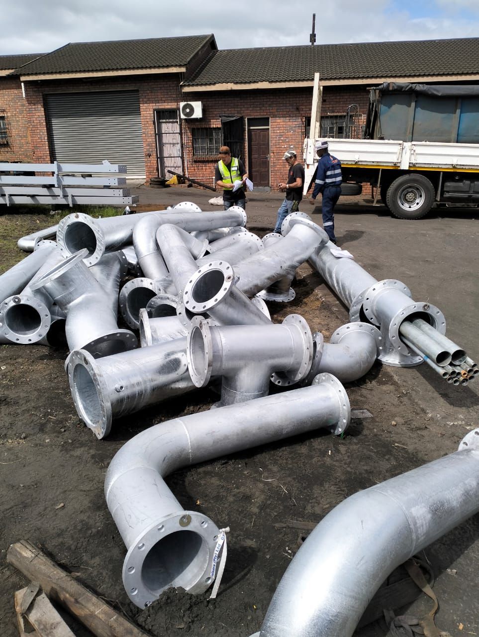 A bunch of pipes are laying on the ground in front of a building