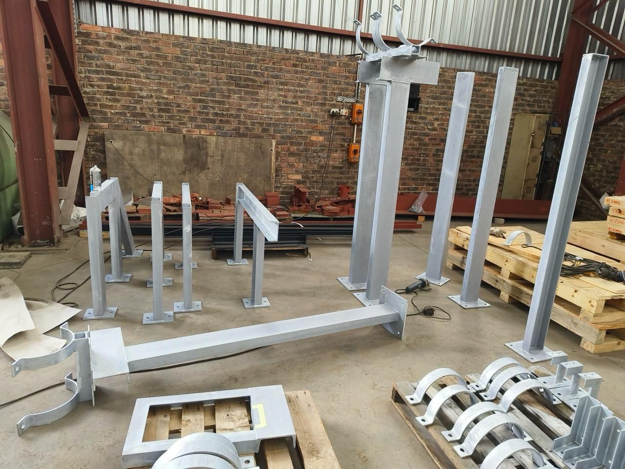 A bunch of metal pieces are sitting on pallets in a warehouse.