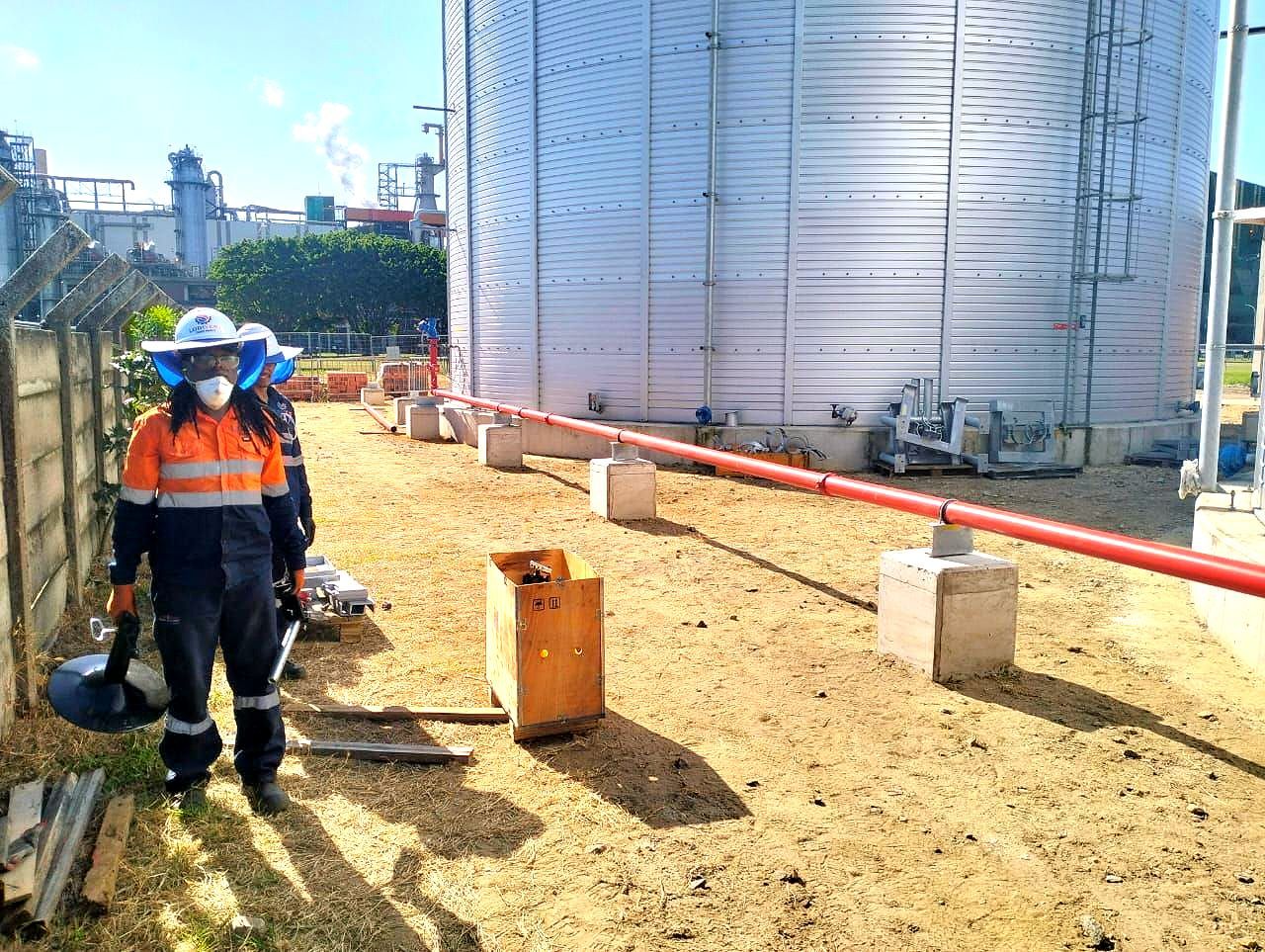 A man wearing a mask is standing in front of a large tank.