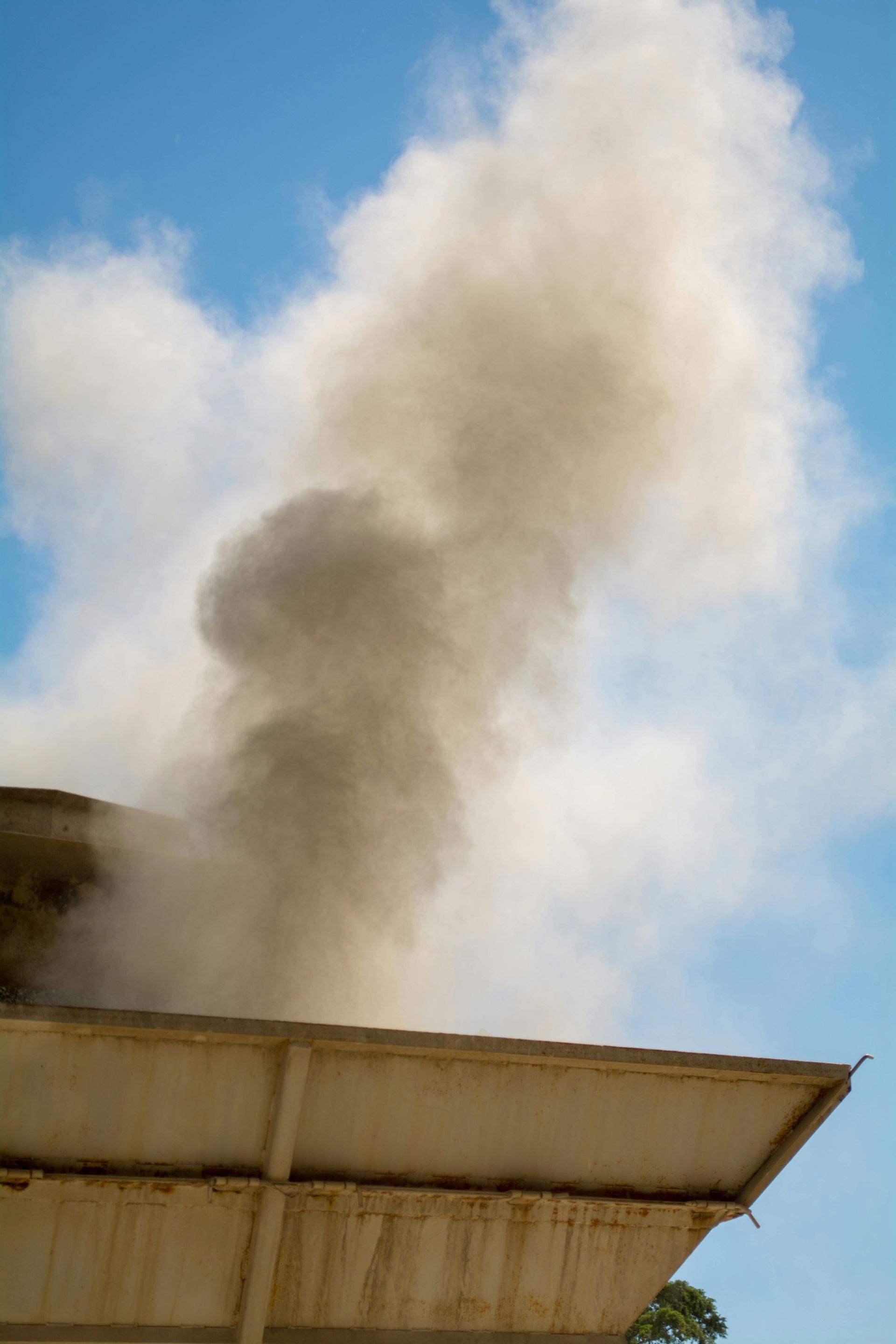Dust is coming out of the roof of a building.