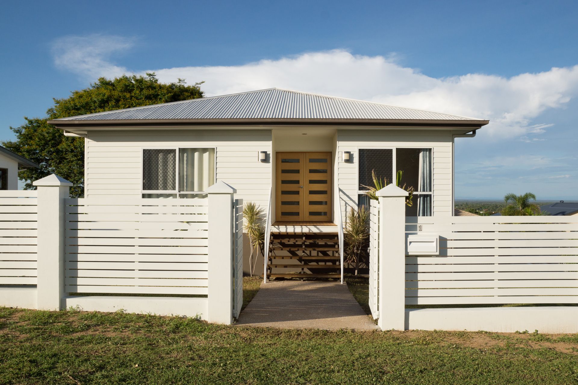 White house with horizontal slat fence; blue sky.