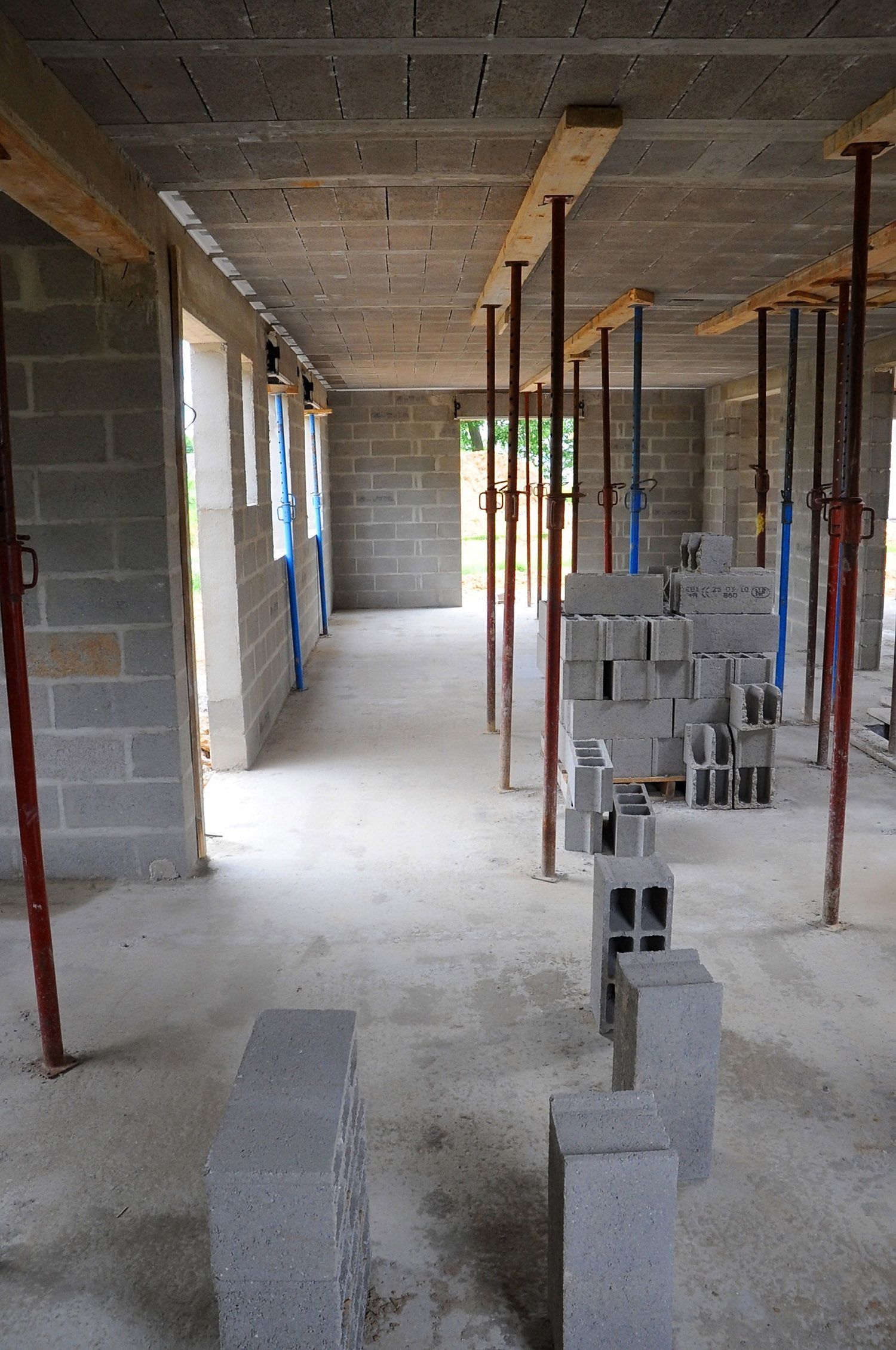 Interior of a building under construction, with gray cinder block walls, scaffolding, and stacked blocks.