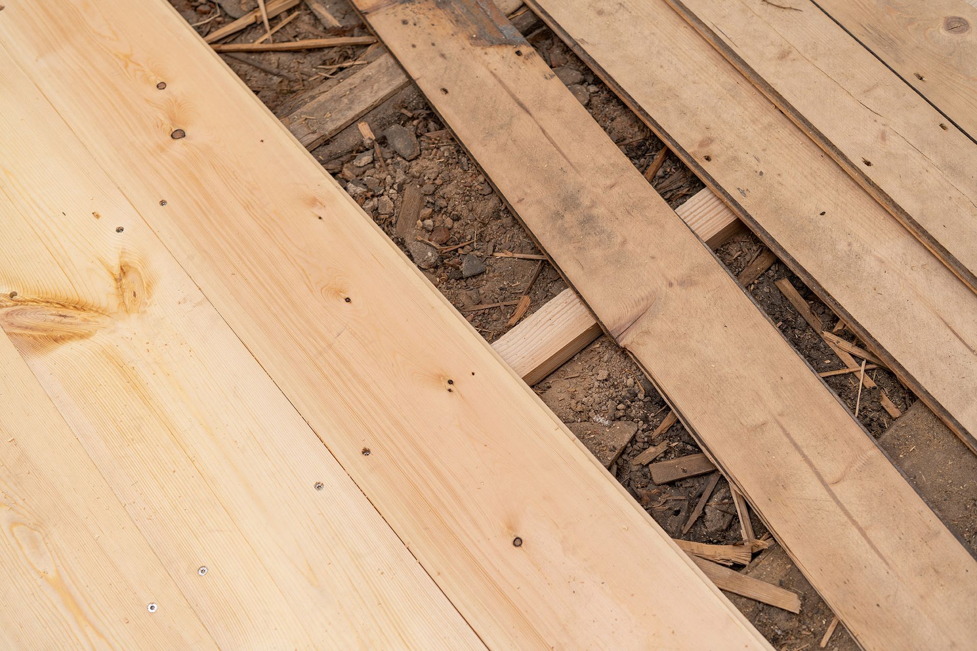 Wooden planks partially cover ground, revealing dirt and wooden supports.