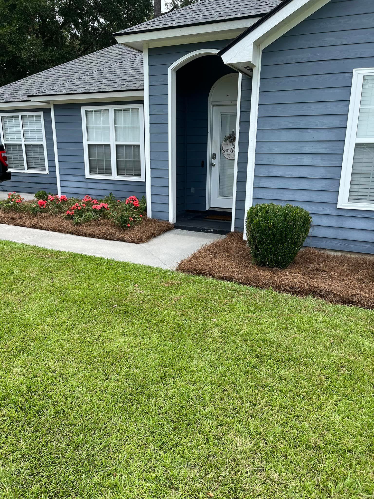 A blue house with a lush green lawn in front of it.