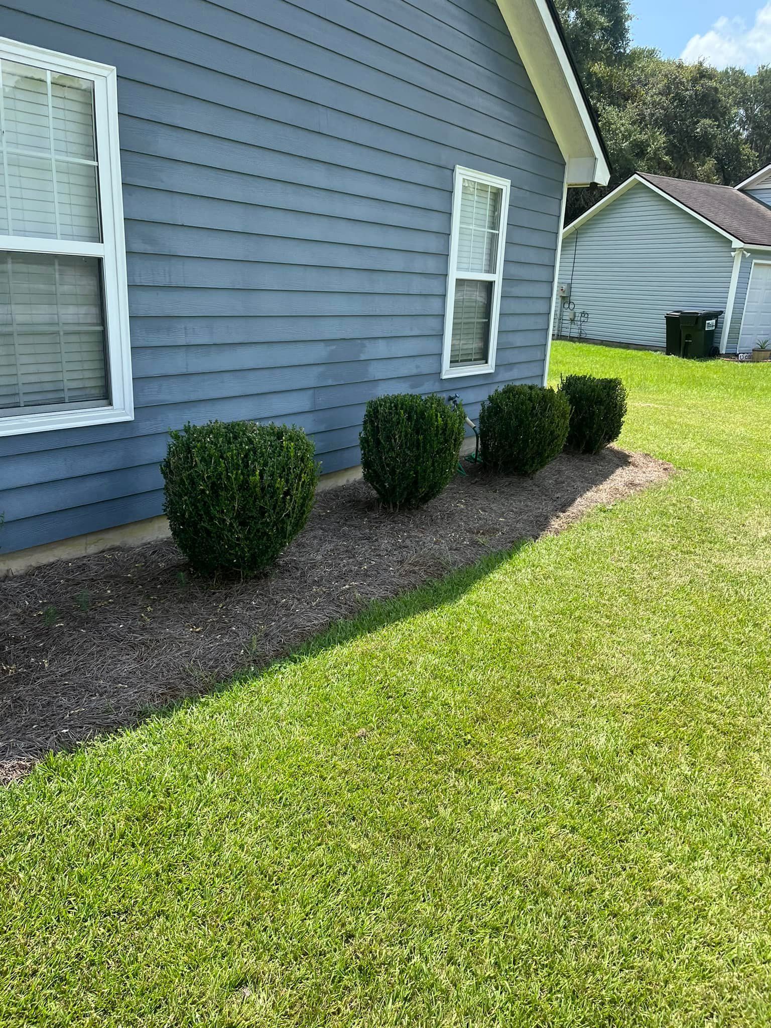 A house with a lush green lawn and bushes in front of it.