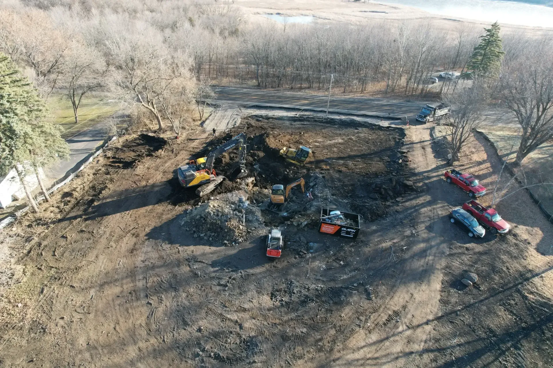 Aerial view of a burnt field with heavy machinery and debris near a charred, cleared area
