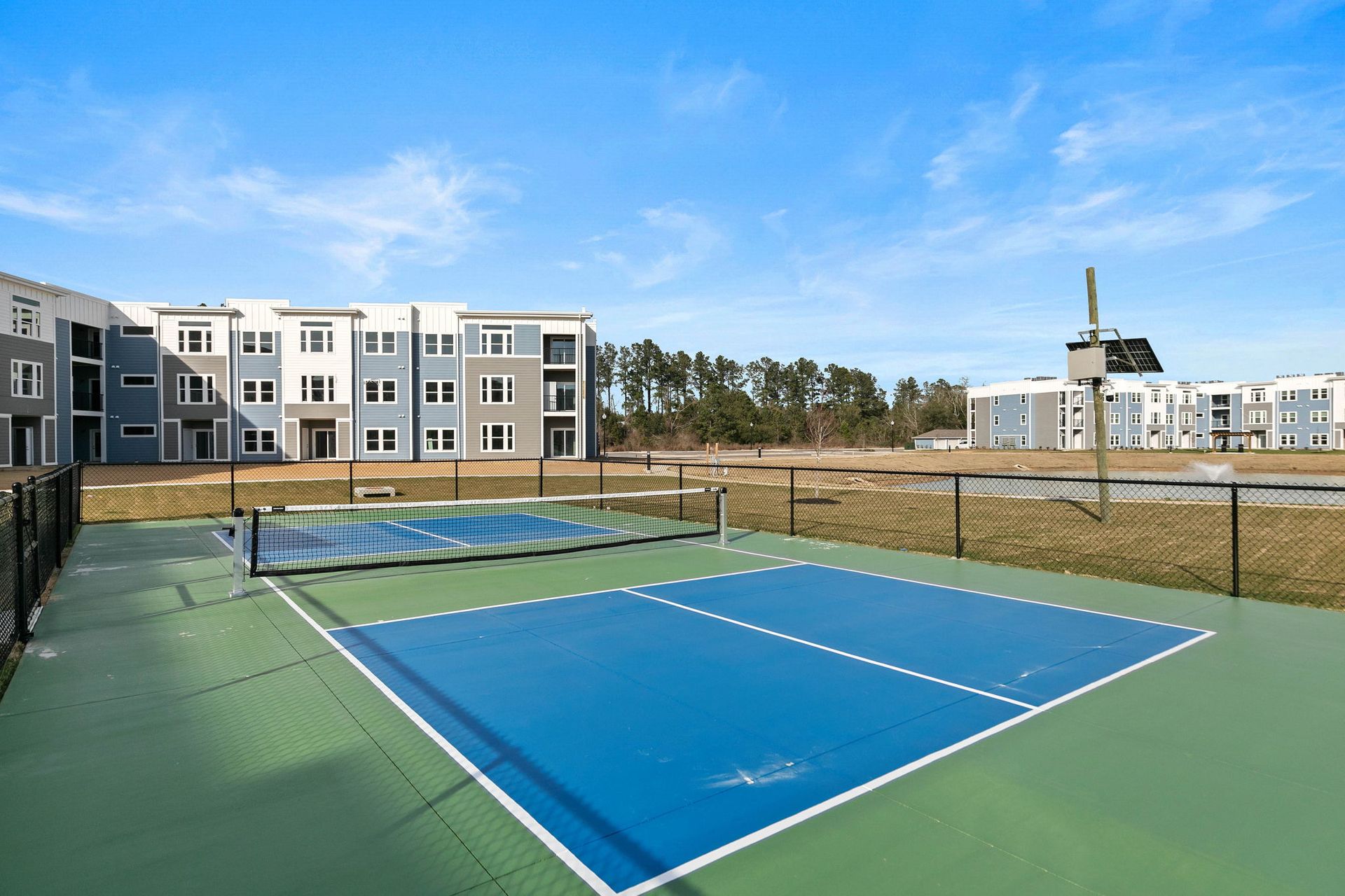 Modern kitchen with white cabinets, stainless steel appliances, and a granite island with blue chairs.
