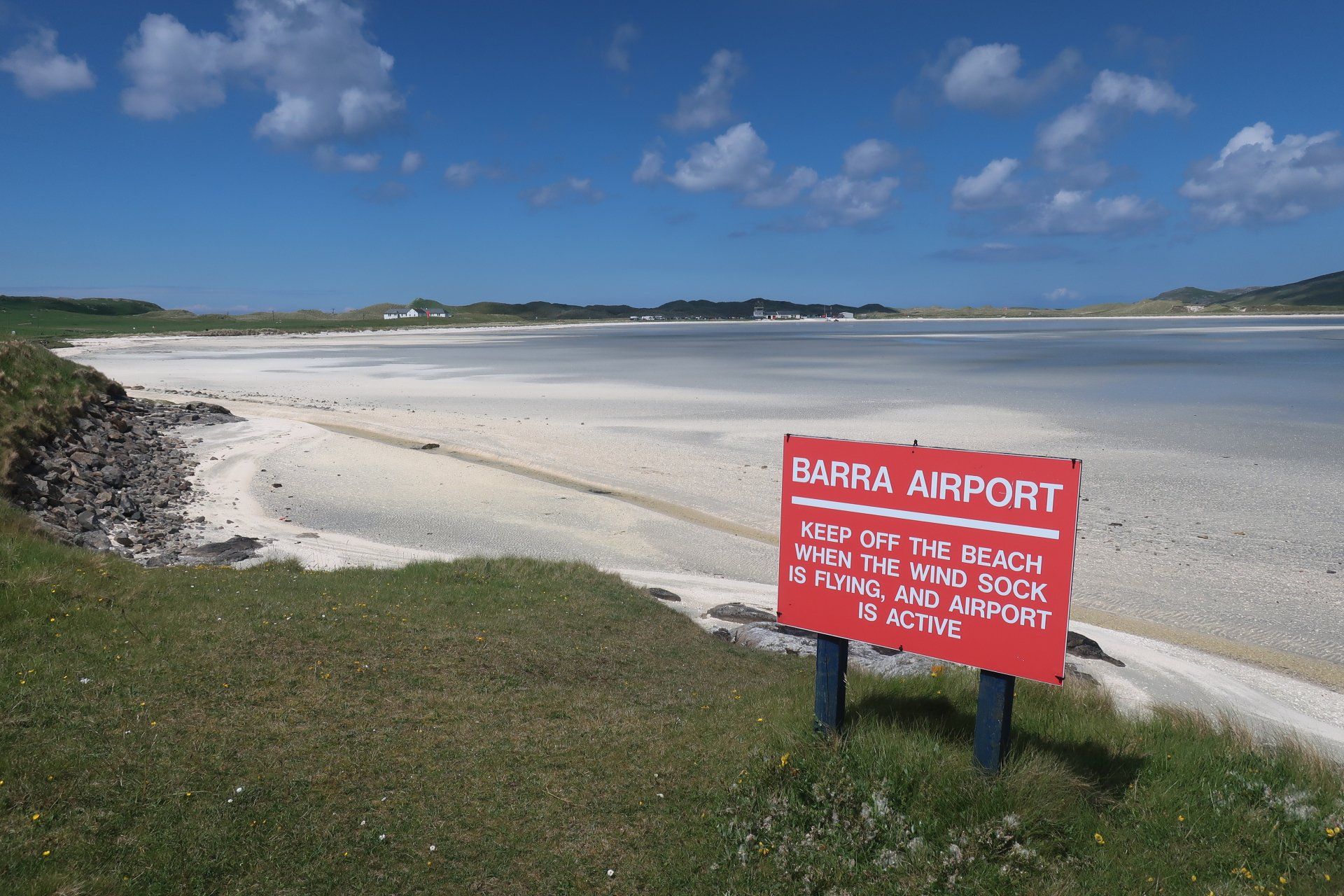 Picture of Barra Airport, which is a beach. Red sign warns to keep of beach when windsock is flying